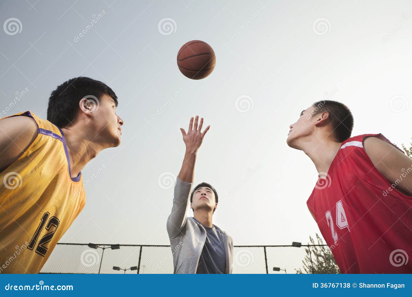 Referee Throwing Ball in the Air, Basketball Players Getting Ready for a Jump Stock Photo