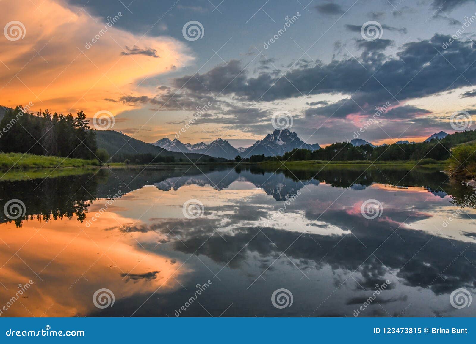 reflection of grand tetons in jackson lake at sunset with beautiful clouds
