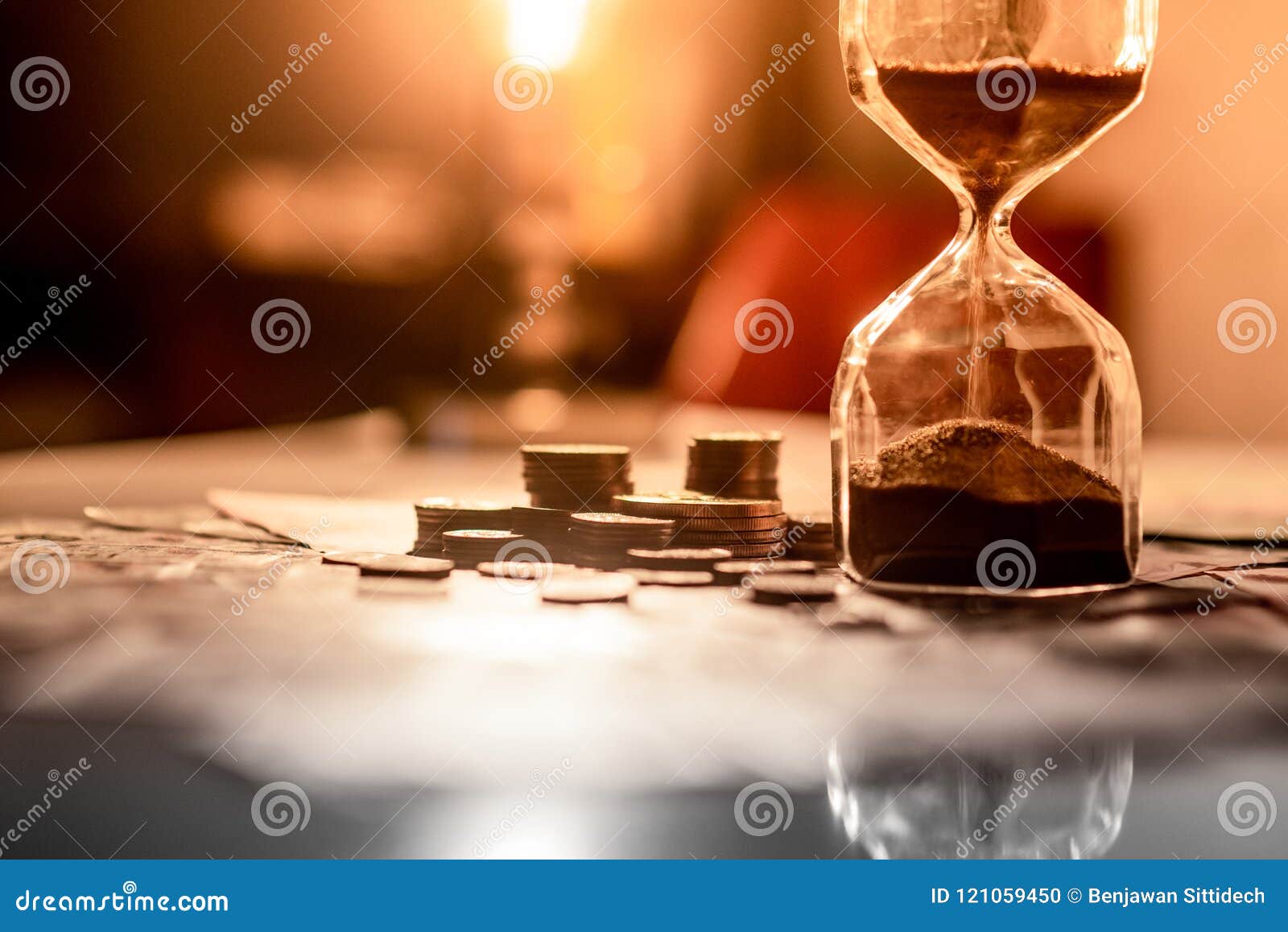 Reflection of Hourglass with Currency on Glowing Table. Stock Photo