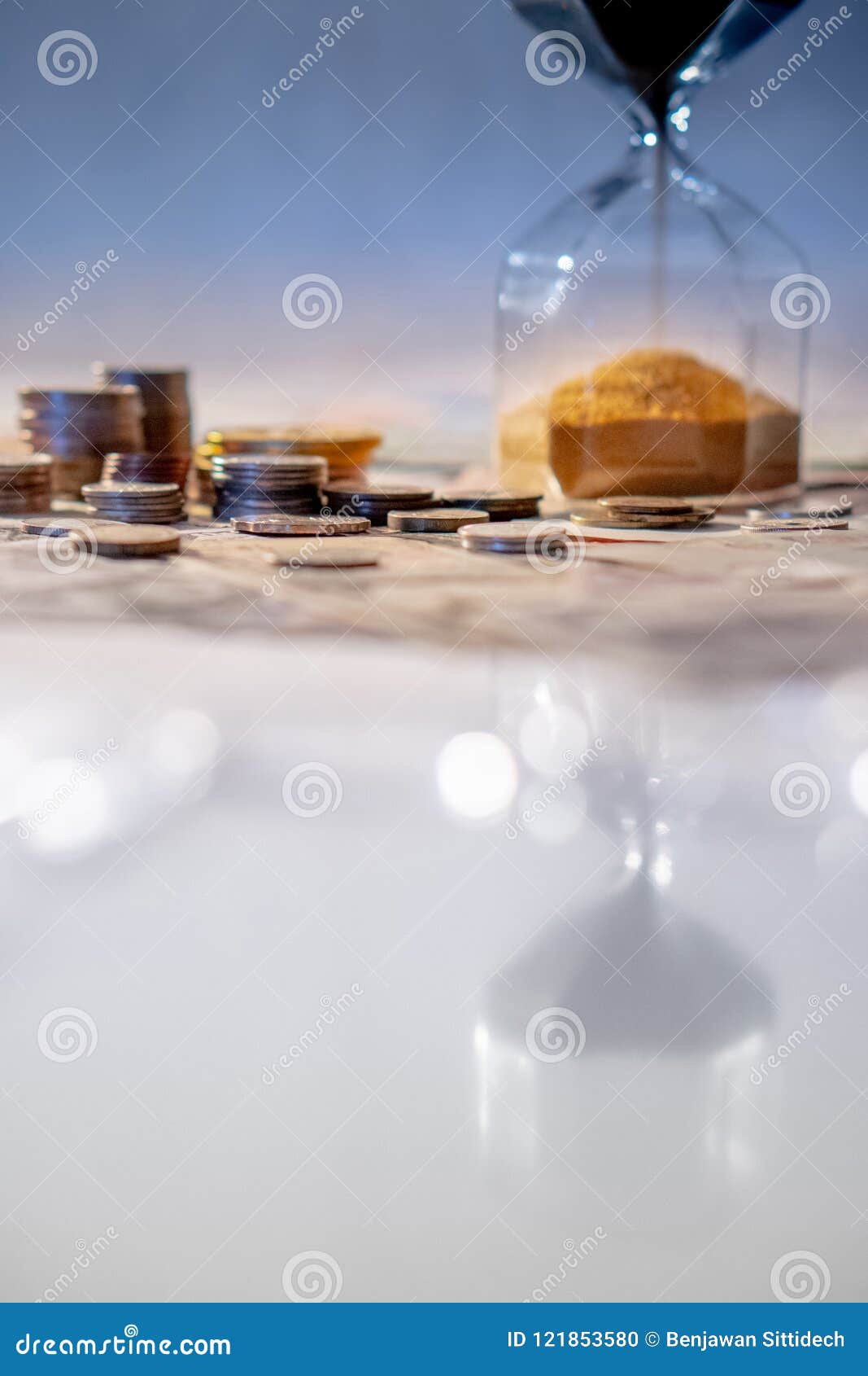 Reflection of Hourglass with Currency on Glowing Table Stock Photo