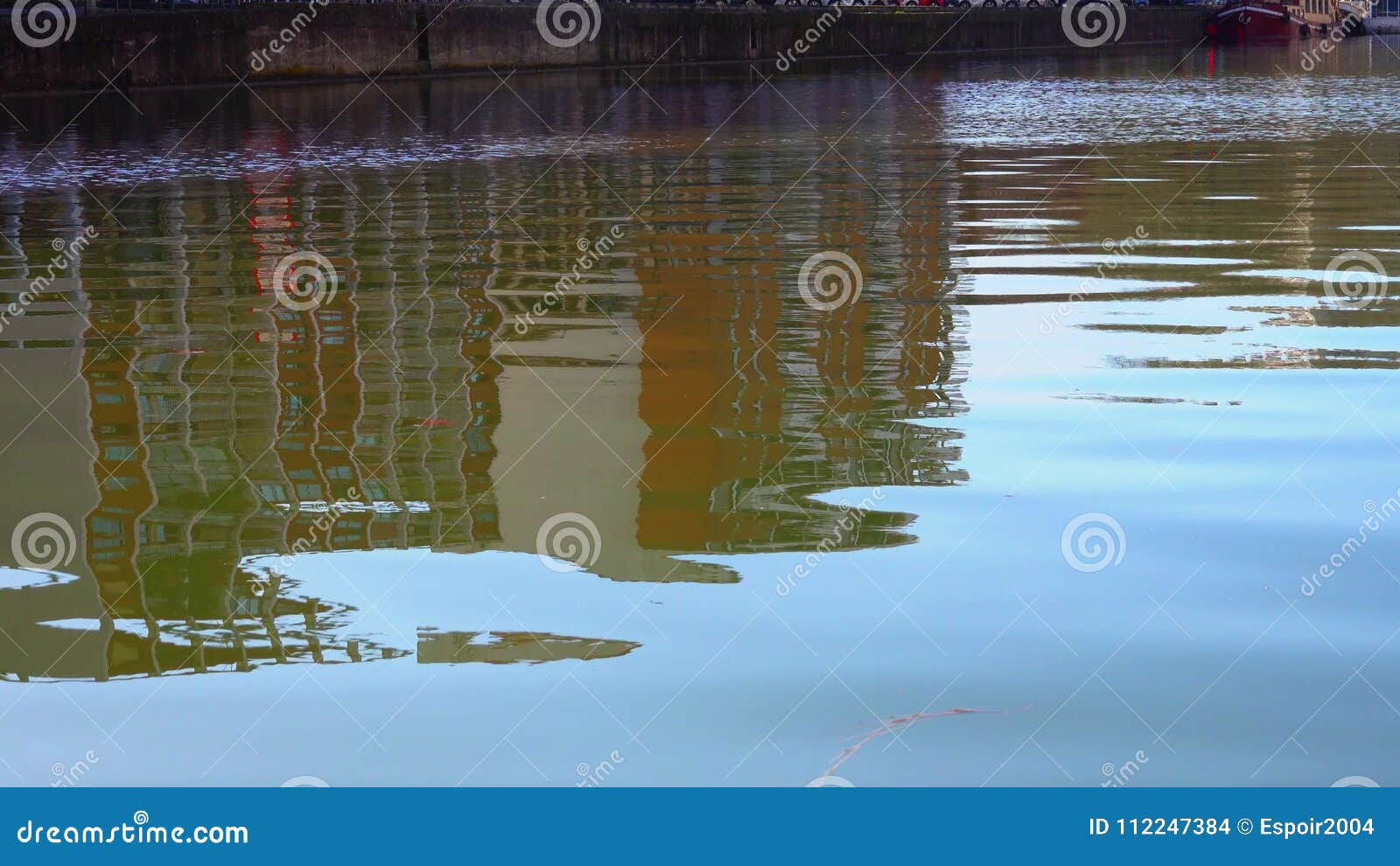 Reflection of Modern Buildings on the Blue Surface of the Water . Stock