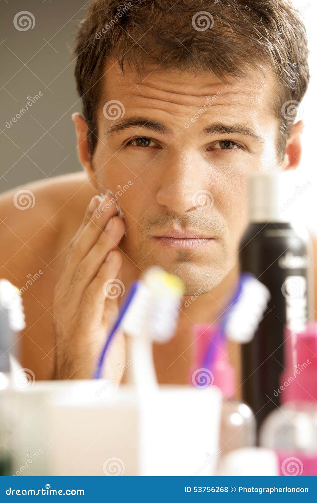 Reflection of Young Man in Mirror Applying Shaving Cream Stock Photo