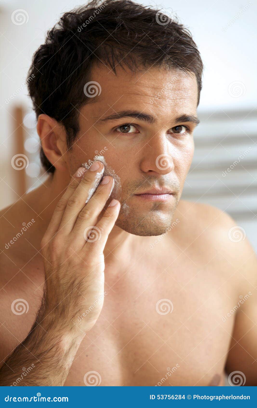 Reflection of Young Man in Mirror Applying Shaving Cream Stock Photo