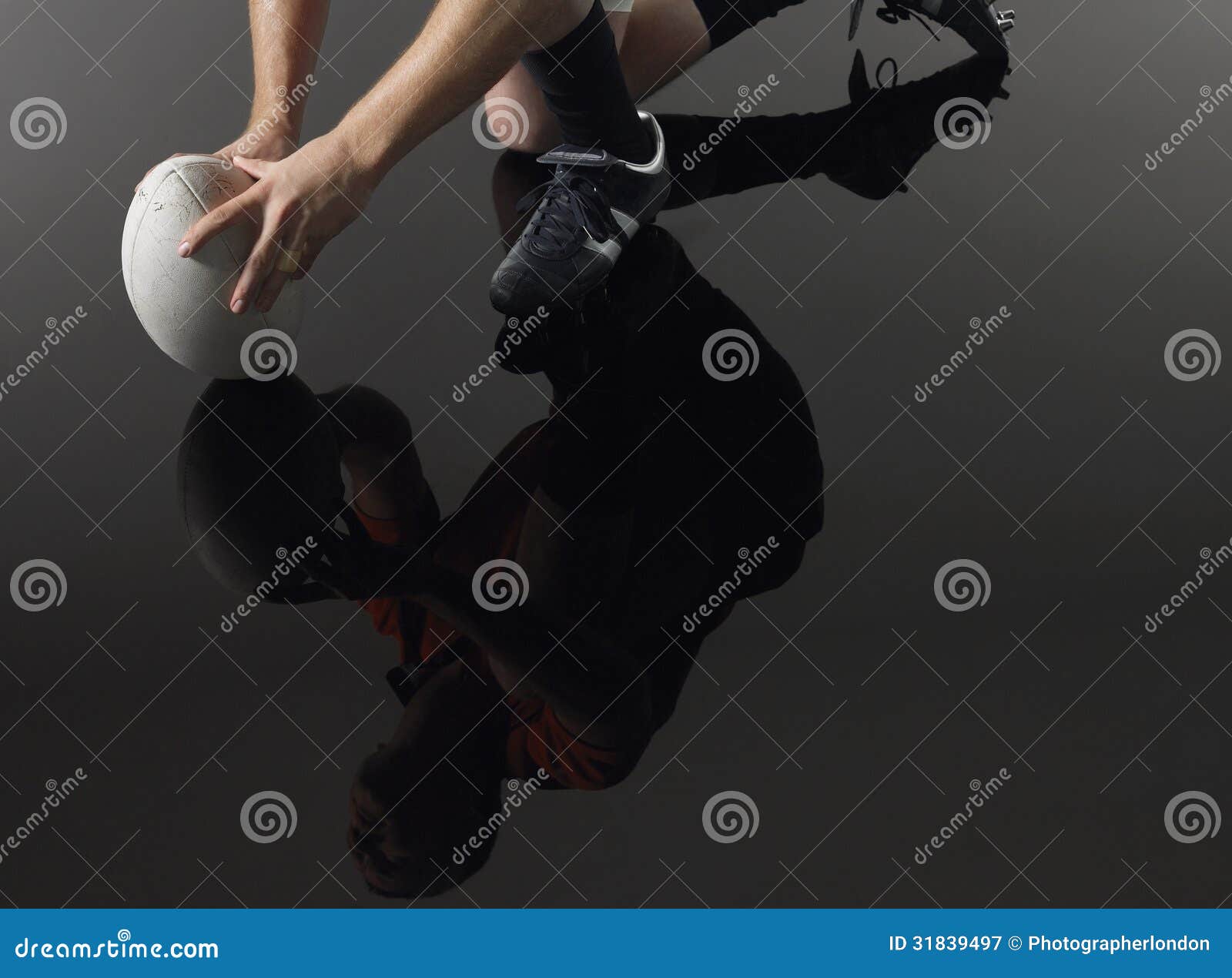 Reflexion av spelaren på ett knä med rugbybollen. Låg avsnitt för Closeup och reflexion av en rugbyspelare som knäfaller på ett knä med bollen