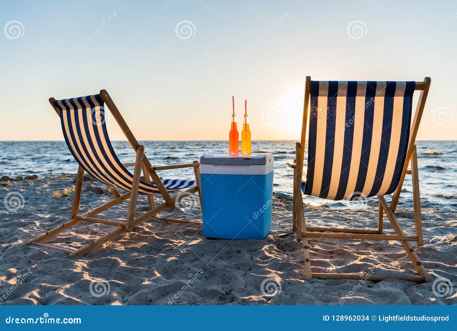 Refreshing Beverages on Cooler and Chaise Lounges on Sandy Beach Stock