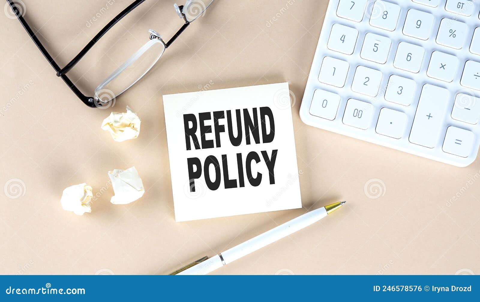 refund policy text on sticky with pen ,calculator and glasses on a beige background