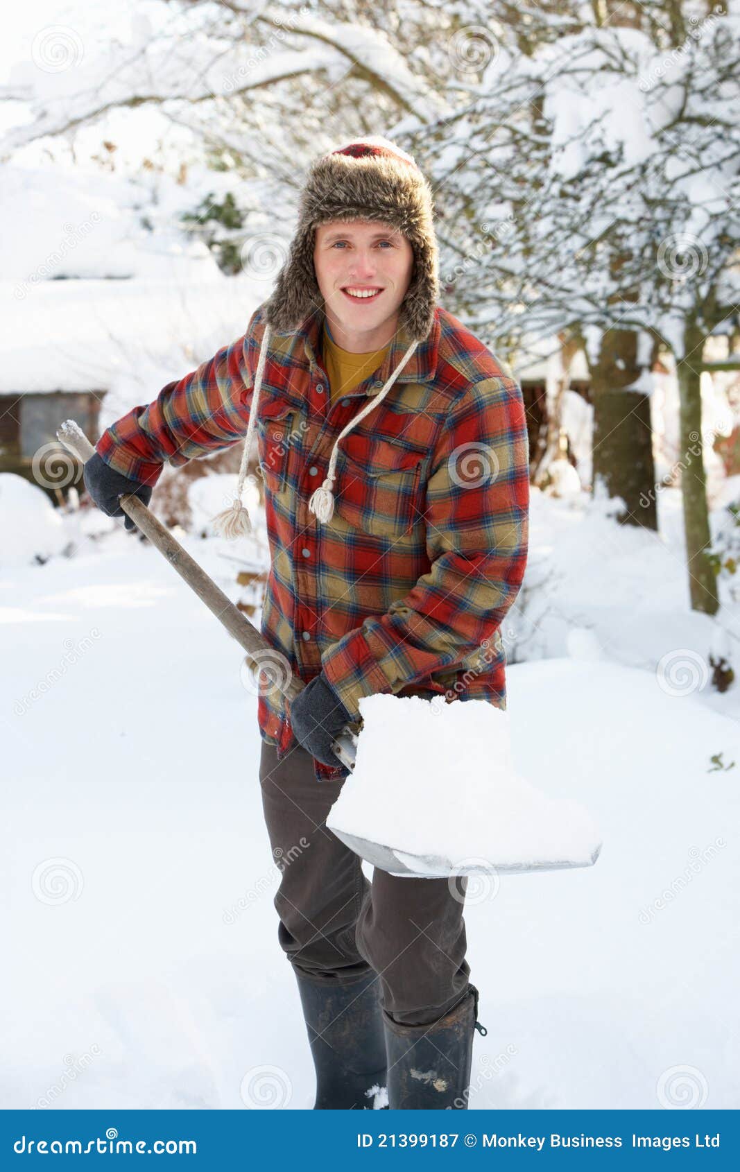 Reinigungschnee des jungen Mannes, der an der Kamera lächelt