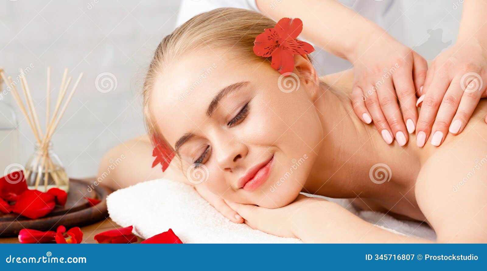 relax and beauty care. smiling girl lies on massage table with flower petals