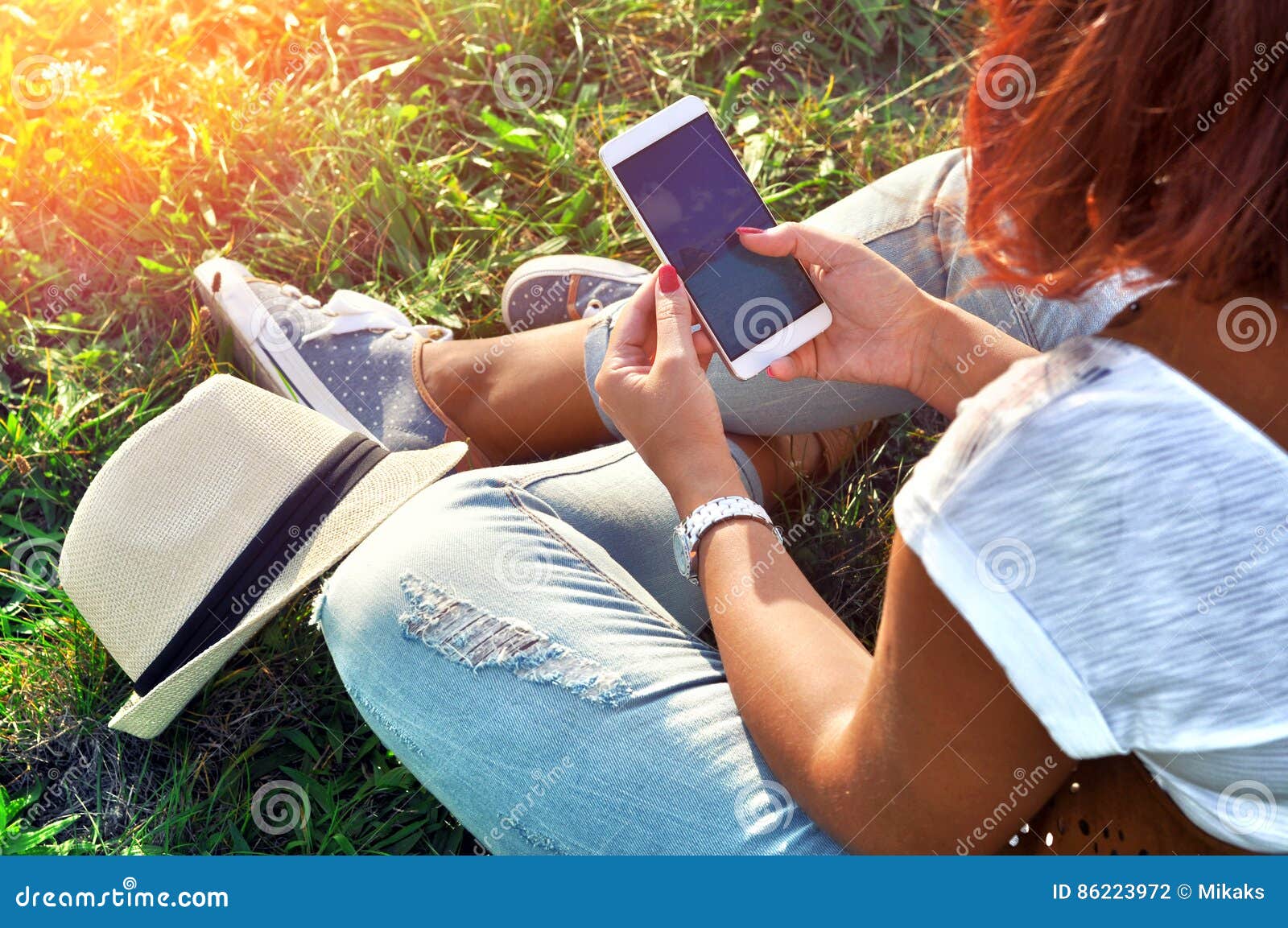 relaxation with a mobile. break time. young woman using cellphone and sitting on the grass.