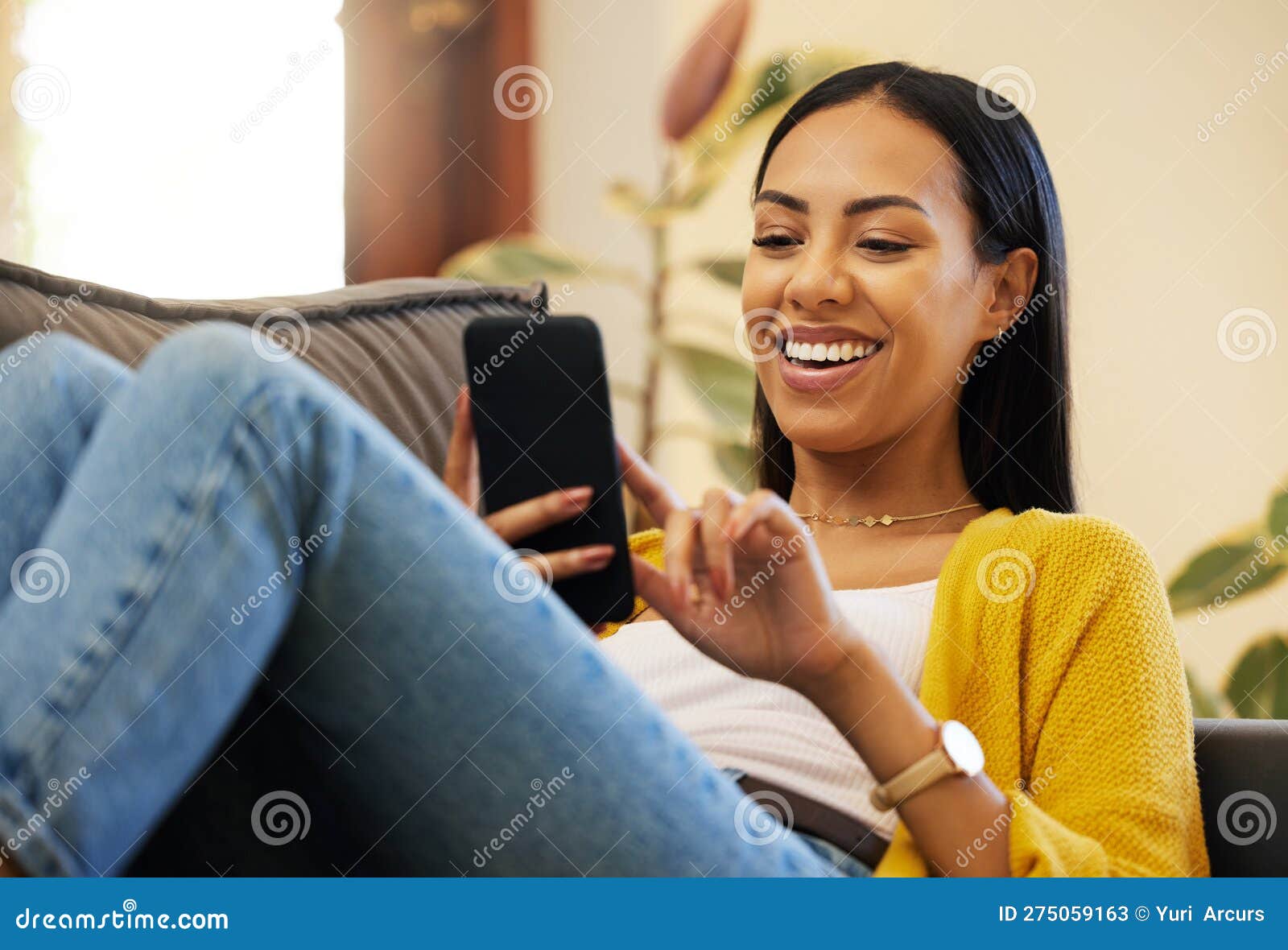 Telefone online e a mulher relaxa mandando mensagens de texto em uma casa  ou apartamento e rindo de memes engraçados da internet nas mídias sociais  sorria feliz e conversando no aplicativo de