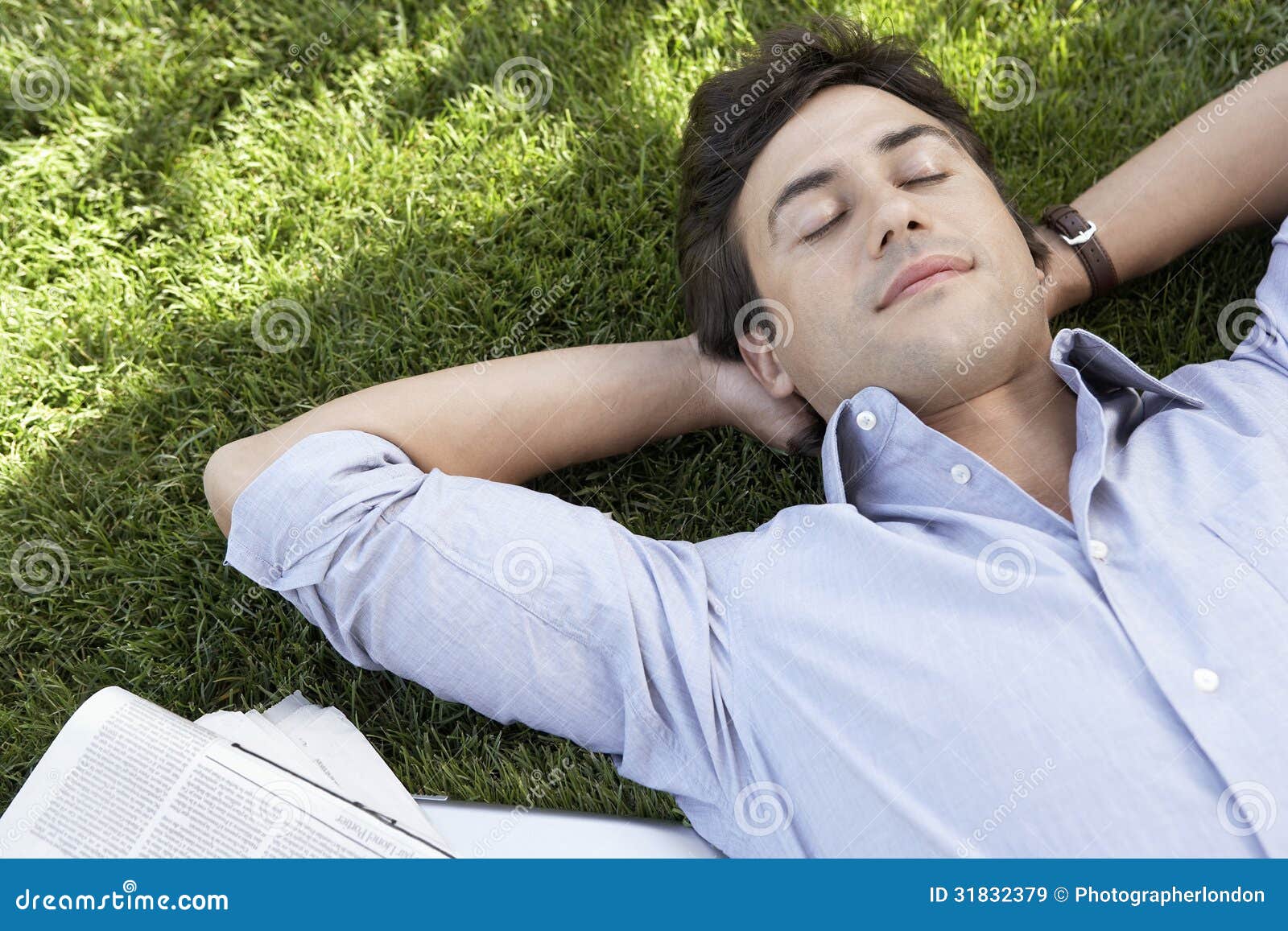 relaxed businessman lying on grass at park
