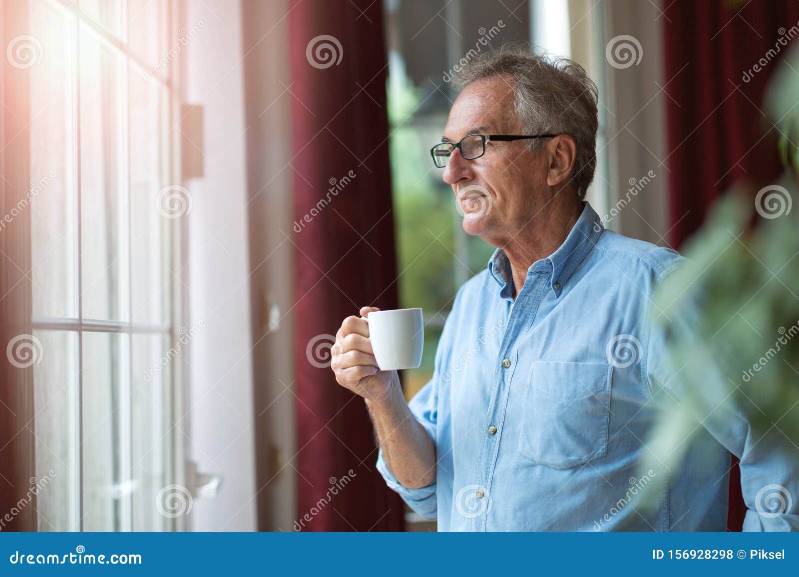 relaxed mature man at home standing by the window