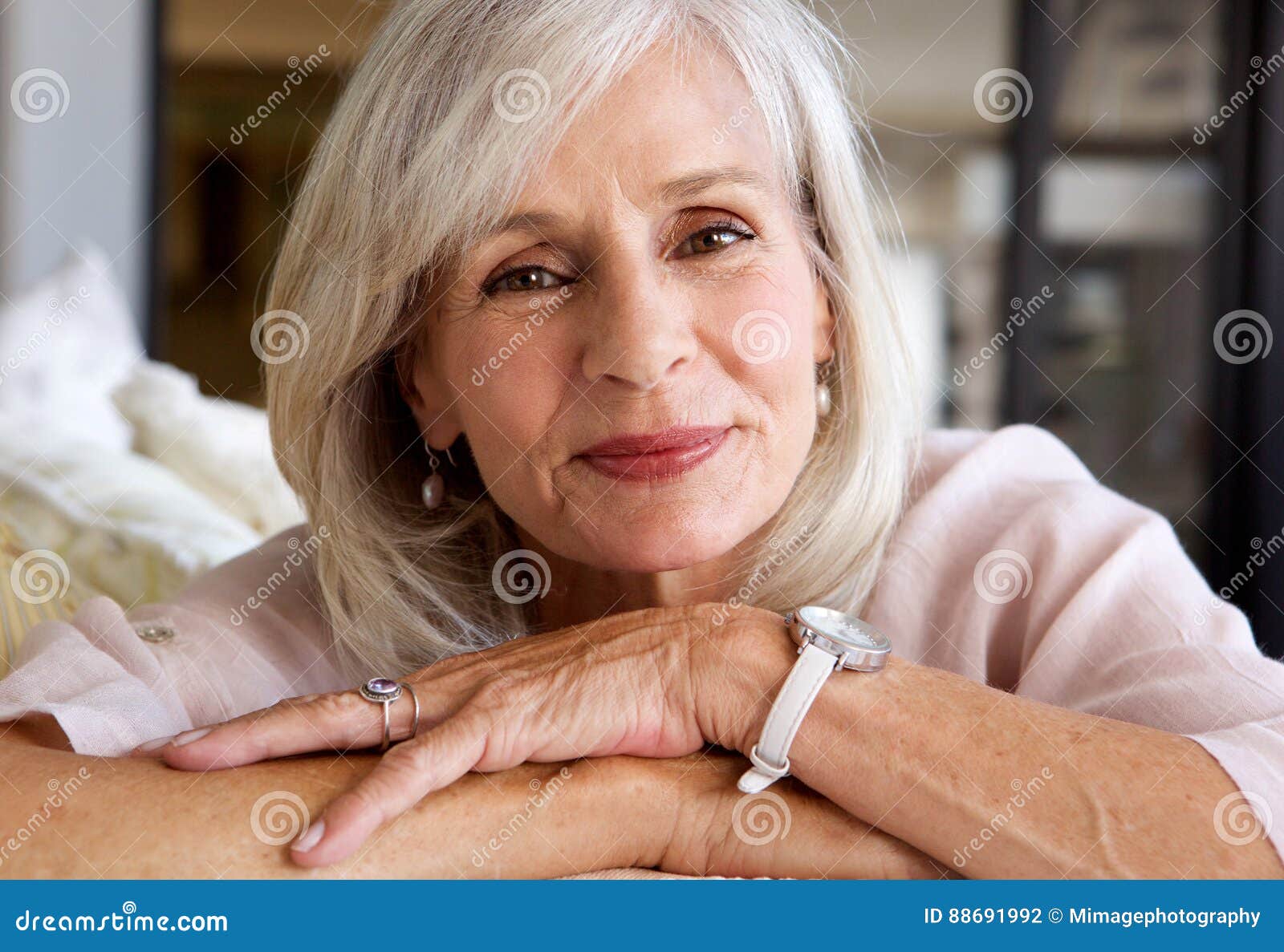 relaxed older woman smiling and sitting on sofa