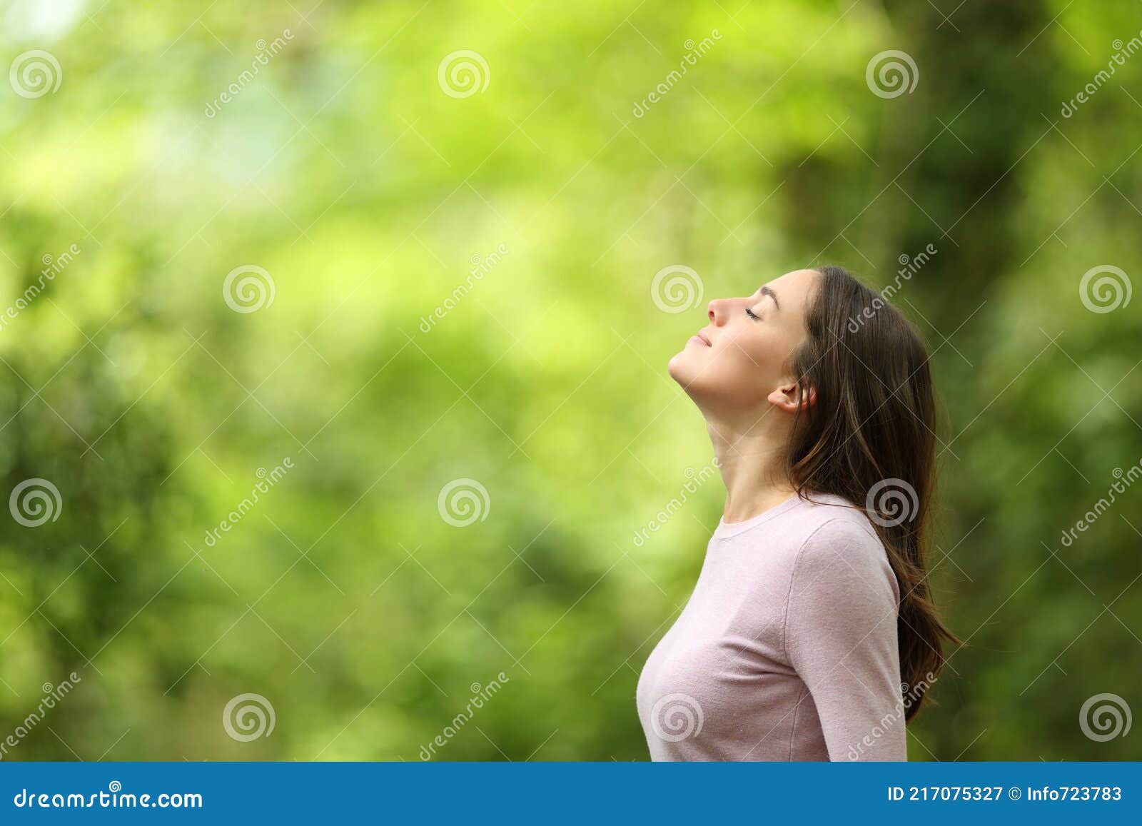 relaxed woman breathing fresh air in a green forest