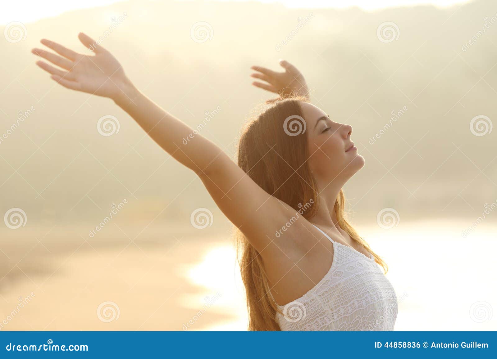 relaxed woman breathing fresh air raising arms at sunrise