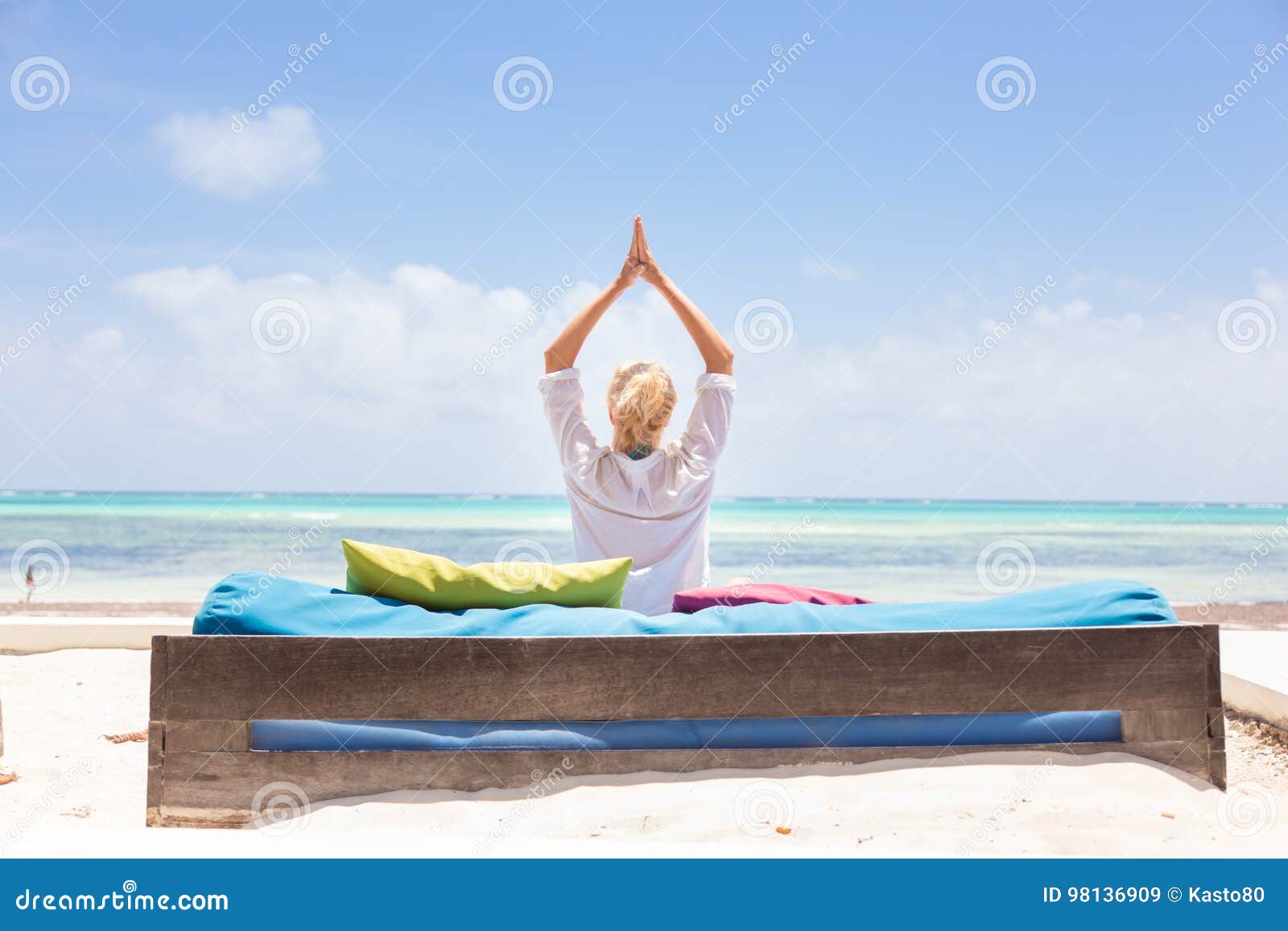 Relaxed woman in luxury lounger, arms rised, enjoying summer vacations on beautiful beach. Lady feeling free, relaxed and happy. Concept of vacations, freedom, happiness, enjoyment and well being.