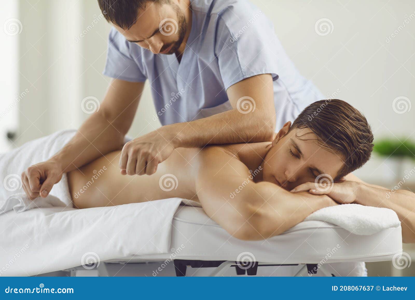 relaxed young man enjoying remedial body massage in spa salon or wellness center