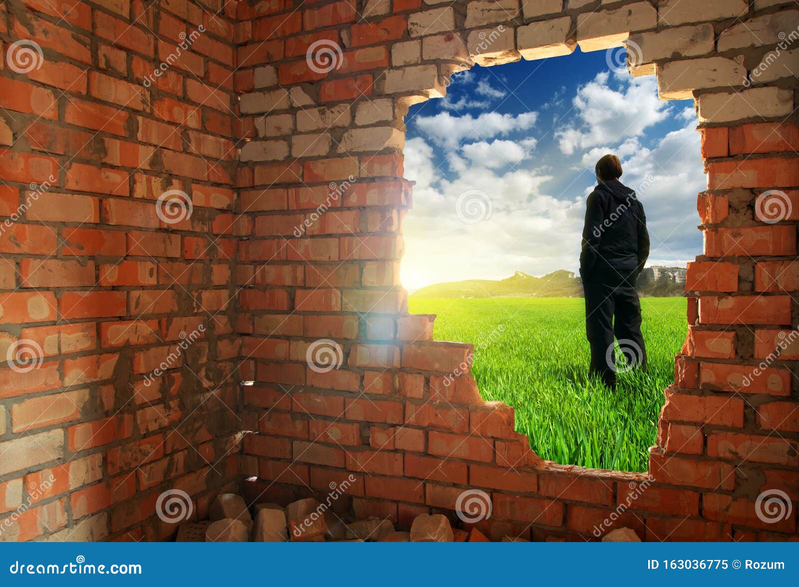 release to freedom. man, standing behind broken brick wall
