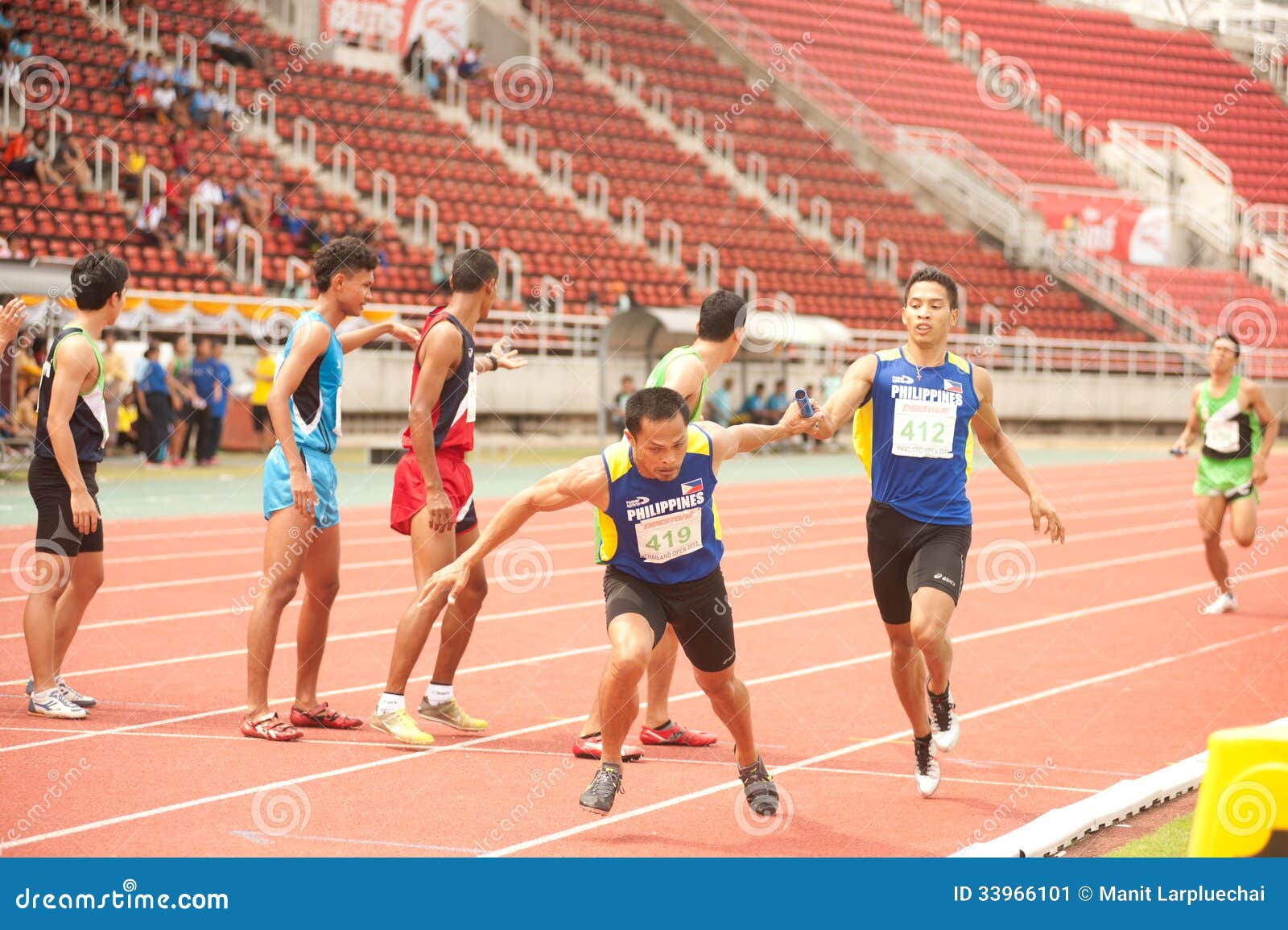 Relè nel campionato atletico aperto 2013 della Tailandia. PHATUMTANI, TAILANDIA – IL 6 SETTEMBRE: I gruppi di azione del giocatore degli uomini del relè 4 X.400 in Tailandia aprono i campionati atletici 2013 allo stadio settembre 6,2013 dell'università di Thammashat nella città di Phatumtani, mezzo della Tailandia.