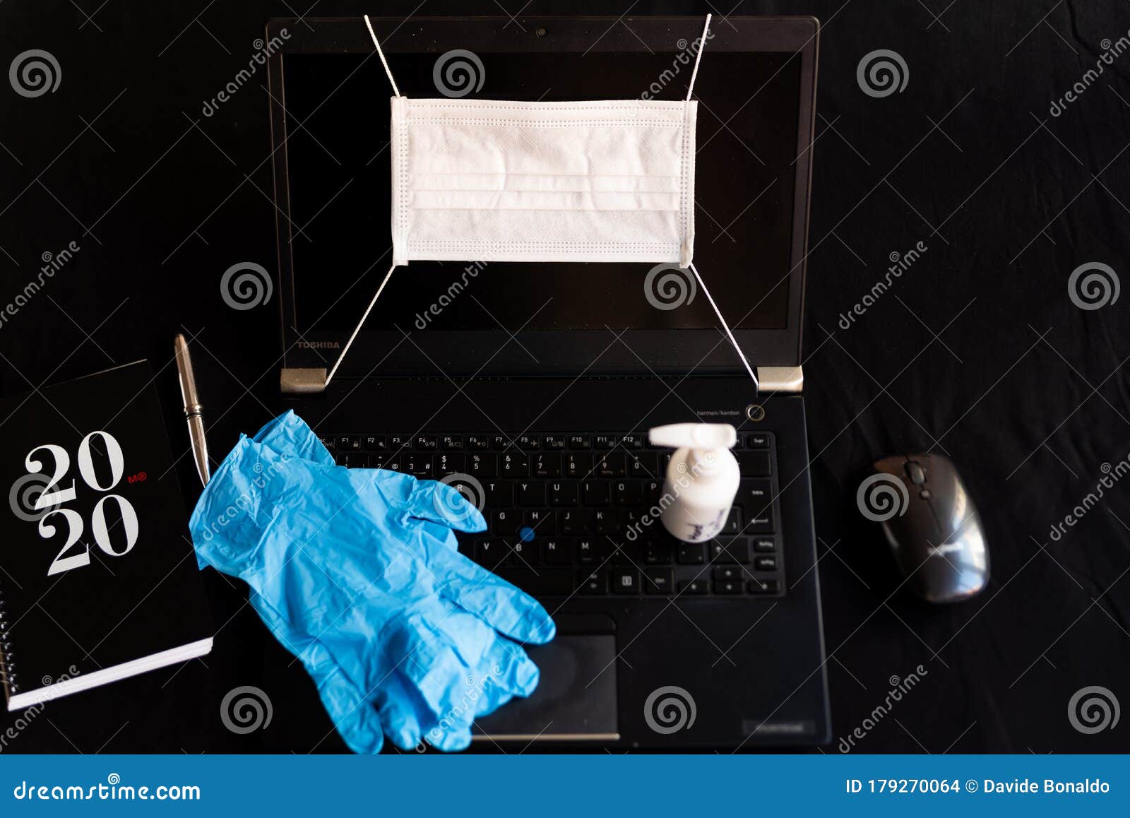 remote work kit on black background home office desk with hand sanitizer and face mask, against the spread of corona virus for