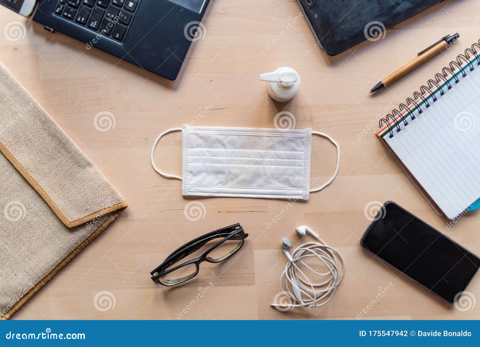 remote work kit on wooden office desk with hand sanitizer and face mask, a solution against the spread of corona virus for