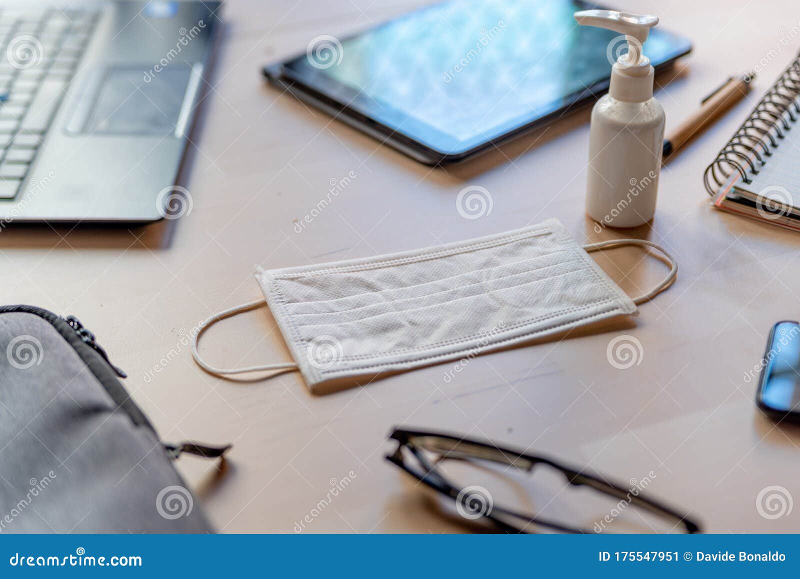 remote work kit on wooden office desk with hand sanitizer and face mask, a solution against the spread of corona virus for