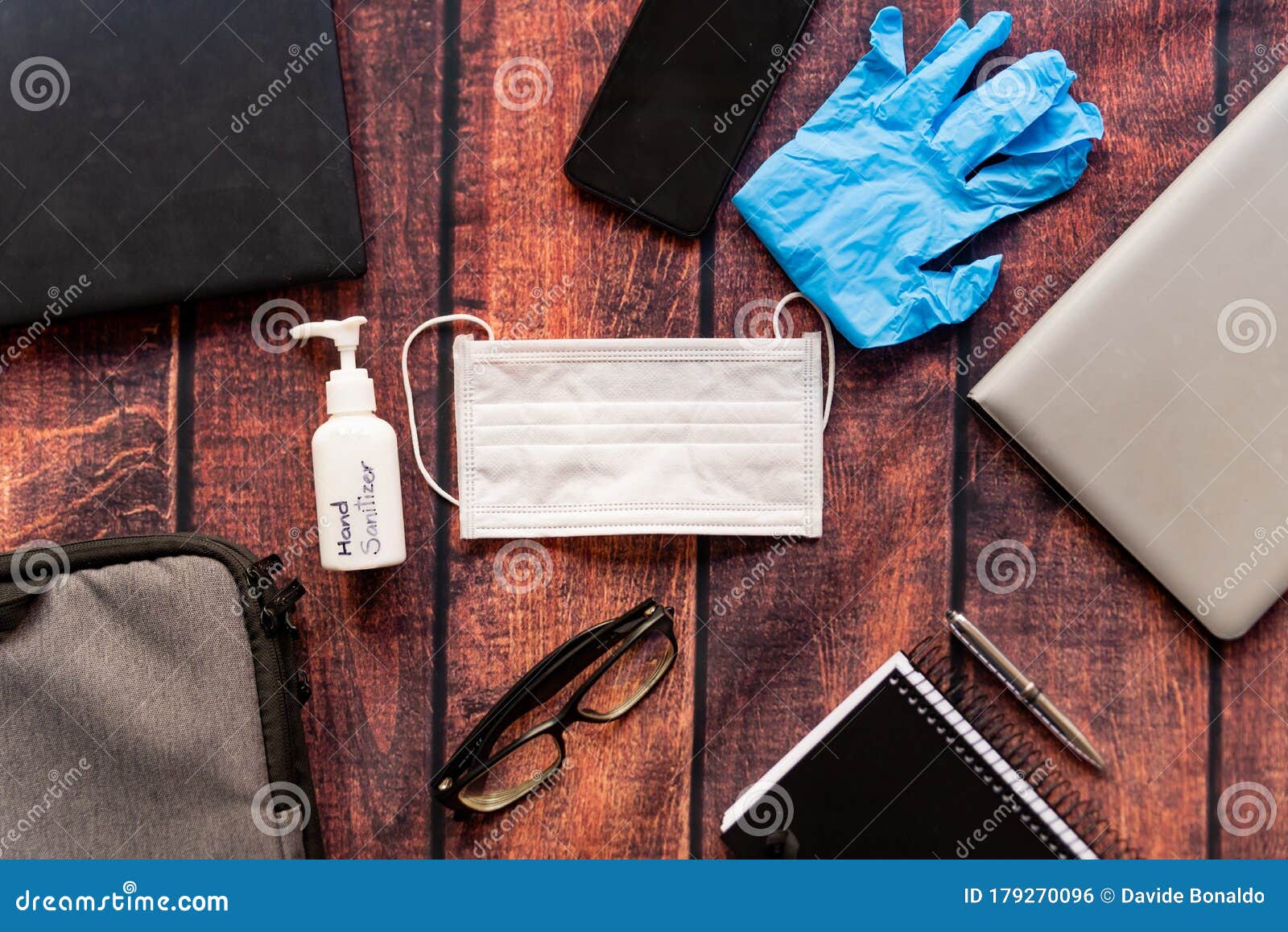 remote work kit on wooden office desk with hand sanitizer and face mask, a solution against the spread of corona virus for