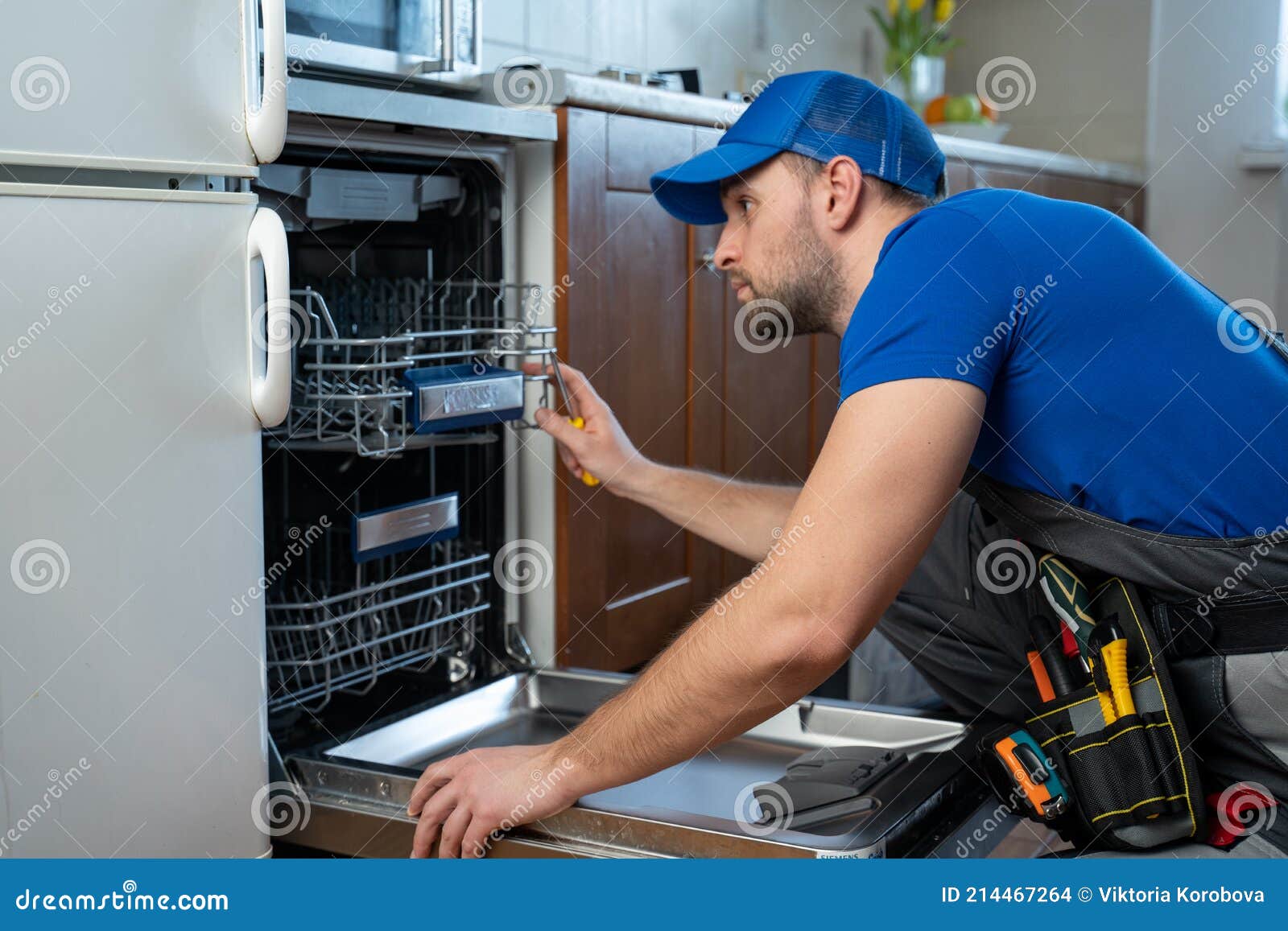 repair of dishwashers. repairman repairing dishwasher in kitchen