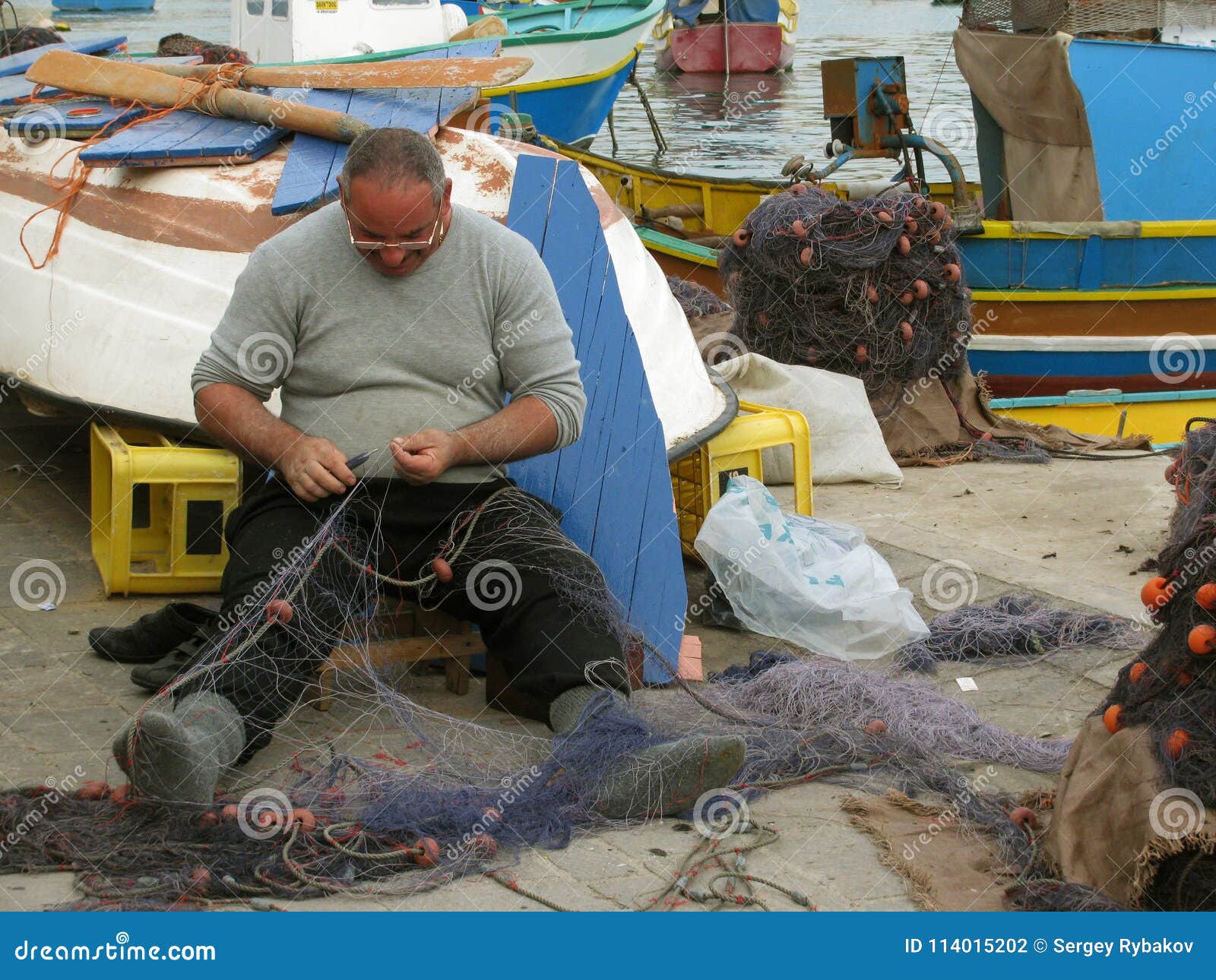 https://thumbs.dreamstime.com/z/repair-fishing-nets-port-malta-marsachlokk-worker-preparing-marsaxlokk-around-traditional-colorful-boats-114015202.jpg