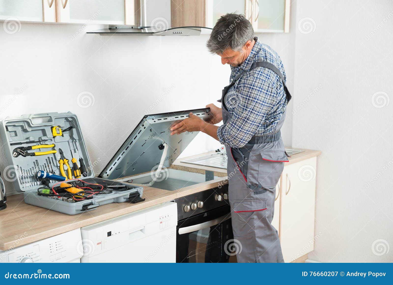 repairman examining stove in kitchen