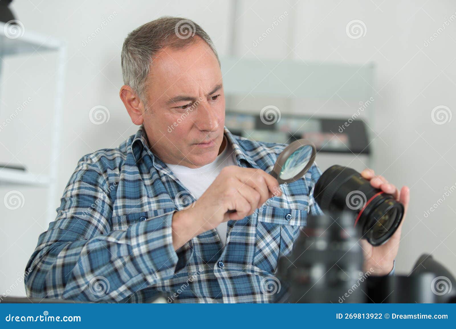 Repairman Looking at Camera Lens through Magnifying Glass Stock Photo