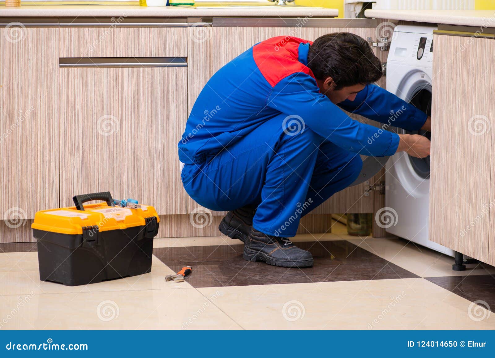 The Repairman Repairing Washing Machine in the Kitchen Stock Photo