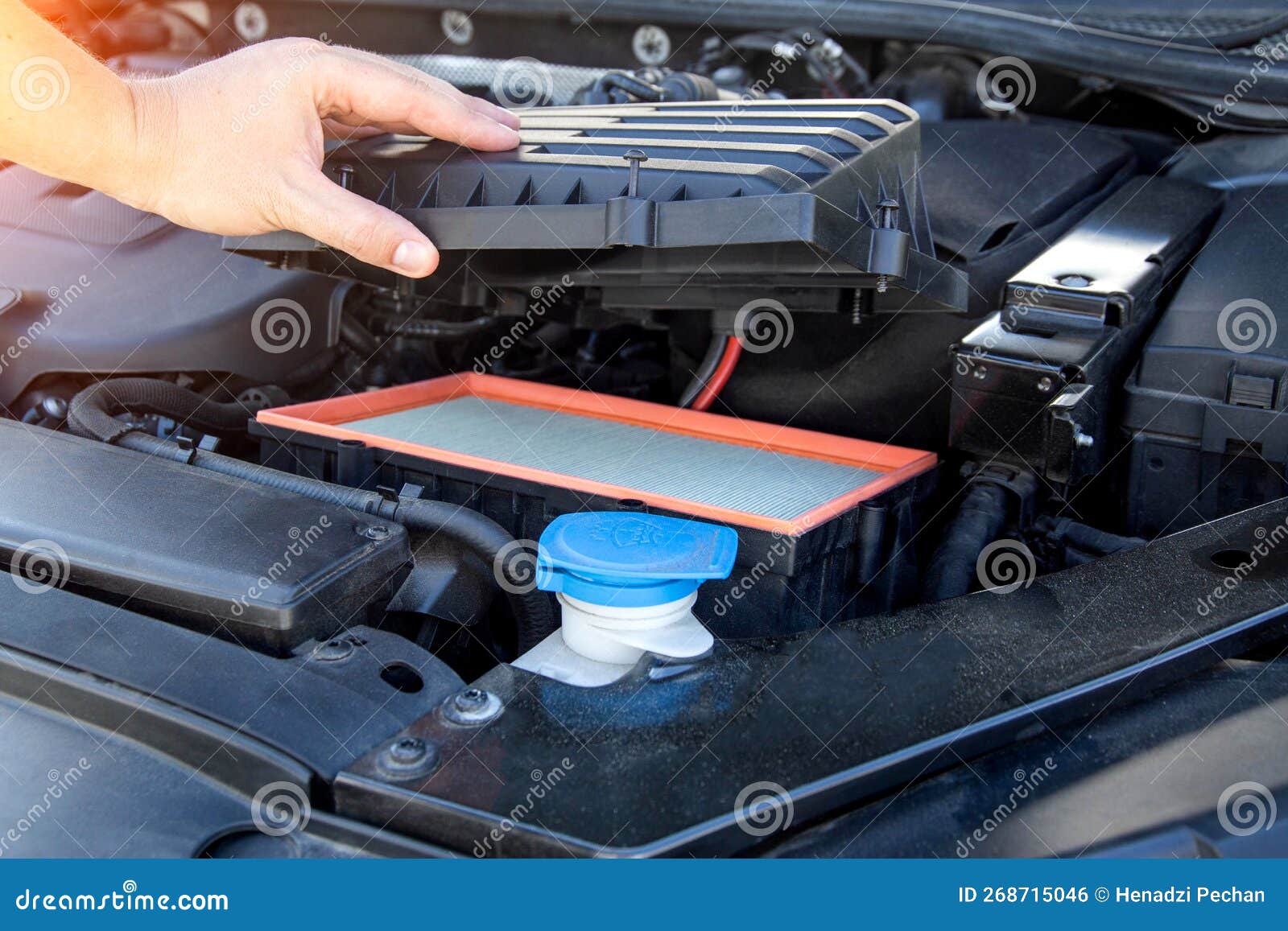 Replacing an Old Dirty Air Filter in the Engine Compartment of a Car