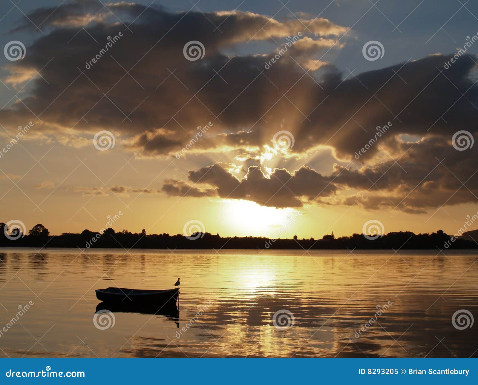 Resplandor solar de la madrugada - amanecer sobre la bahía. El amanecer sobre la bahía, sol de levantamiento siluetea el bote en descanso.