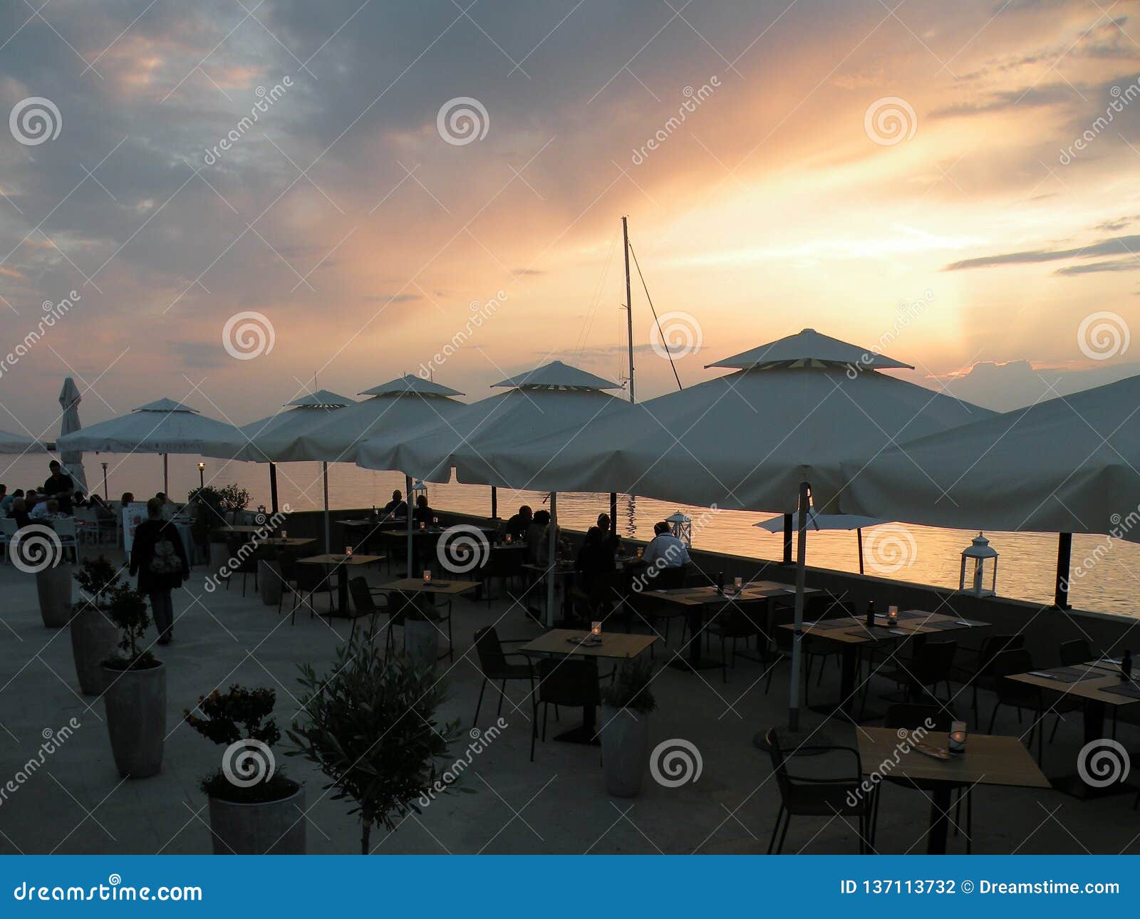 Restaurant by the Sea with Sunset, People at Dinner, Tables Under White ...