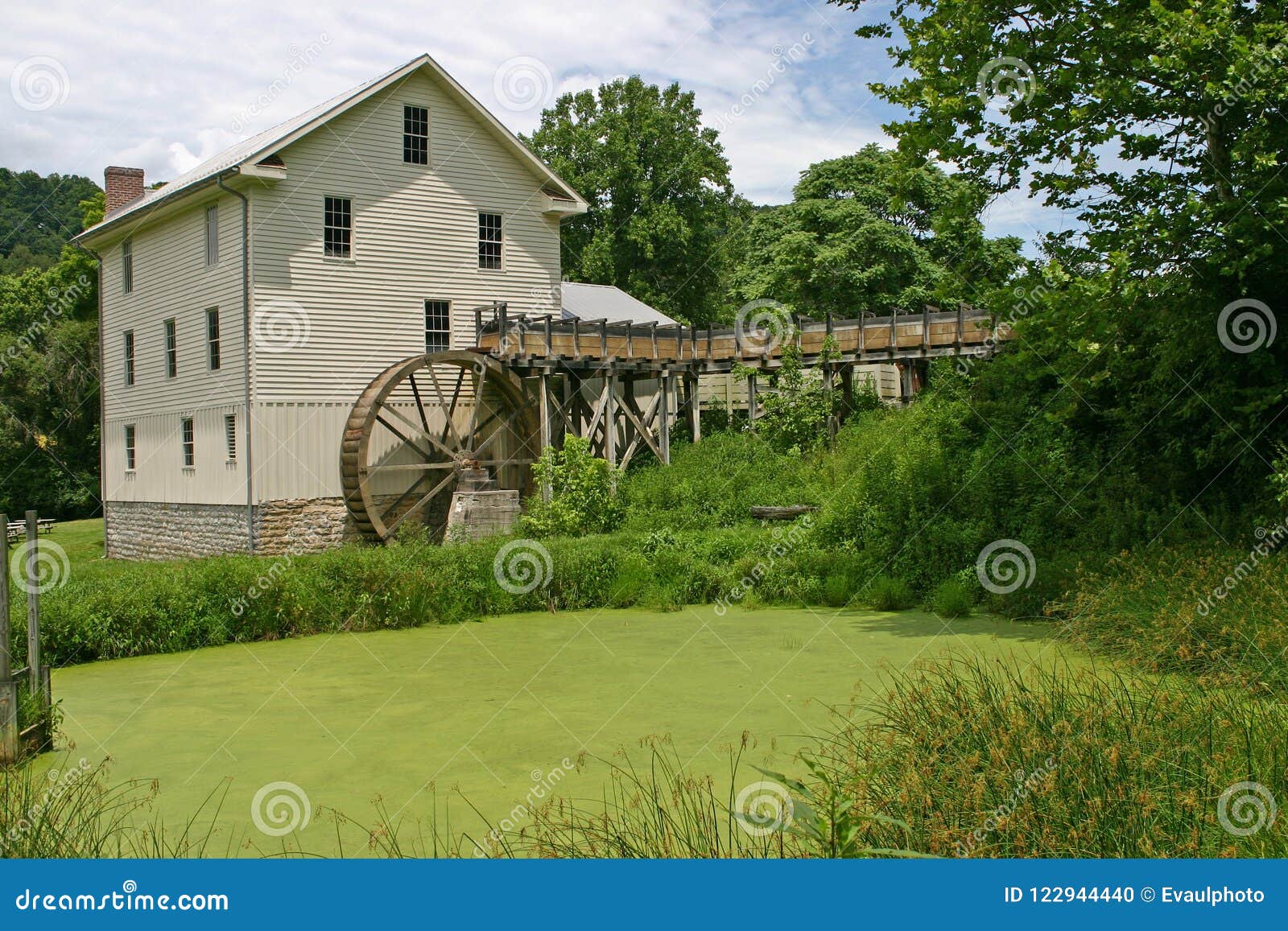 restored white gristmill and green pond