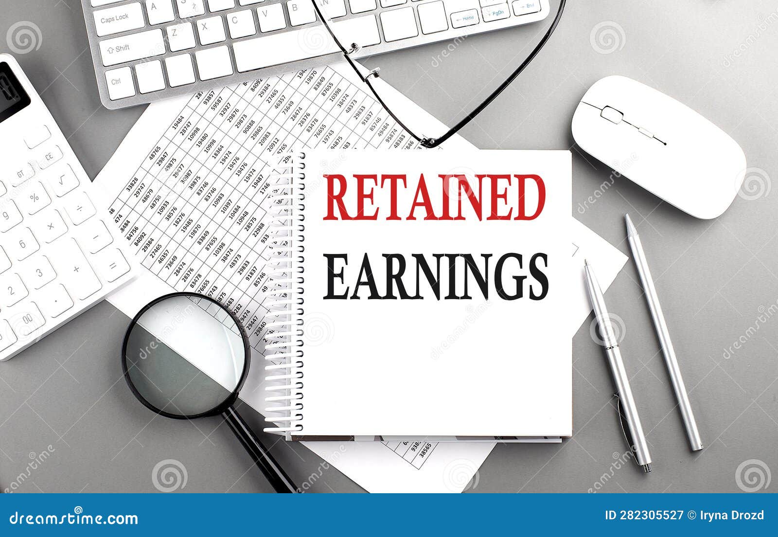retained earnings text on notepad on chart with keyboard and calculator on grey background