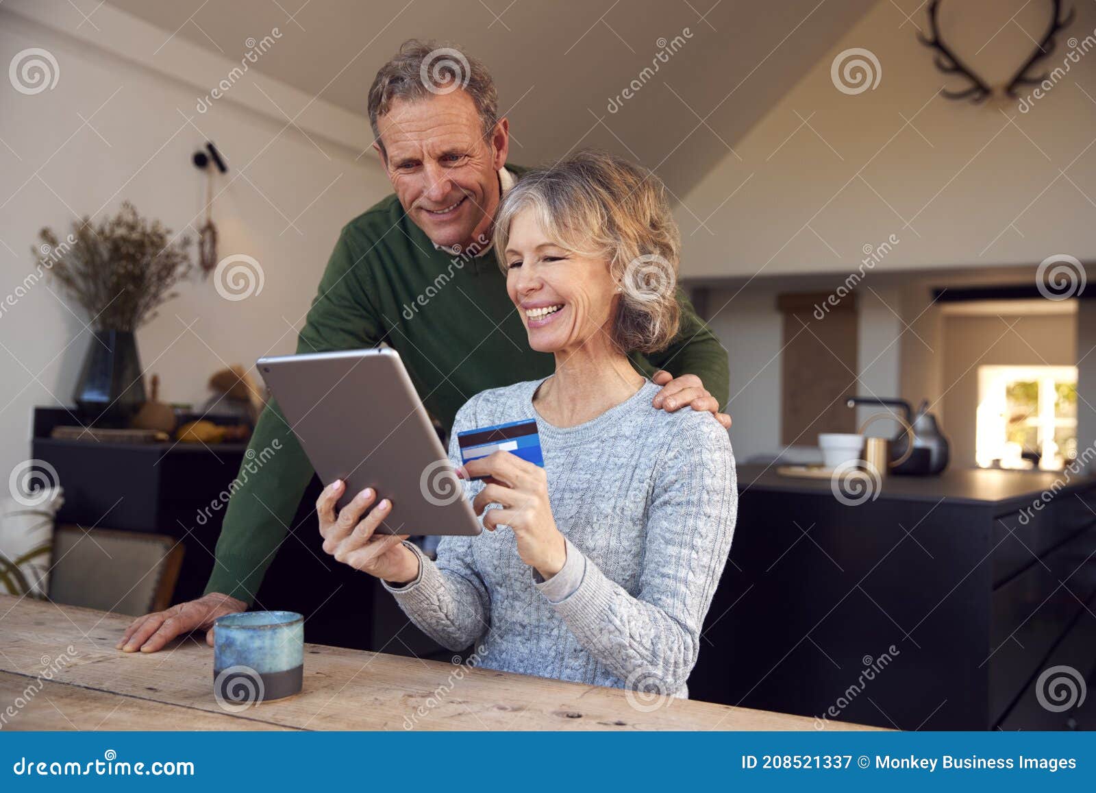 retired senior couple at home buying products or services online with digital tablet and credit card