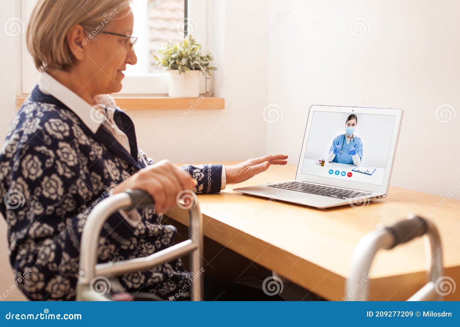 retired senior elderly woman with mobility problem talking to uk nhs gp female doctor via virtual telemedicine video call