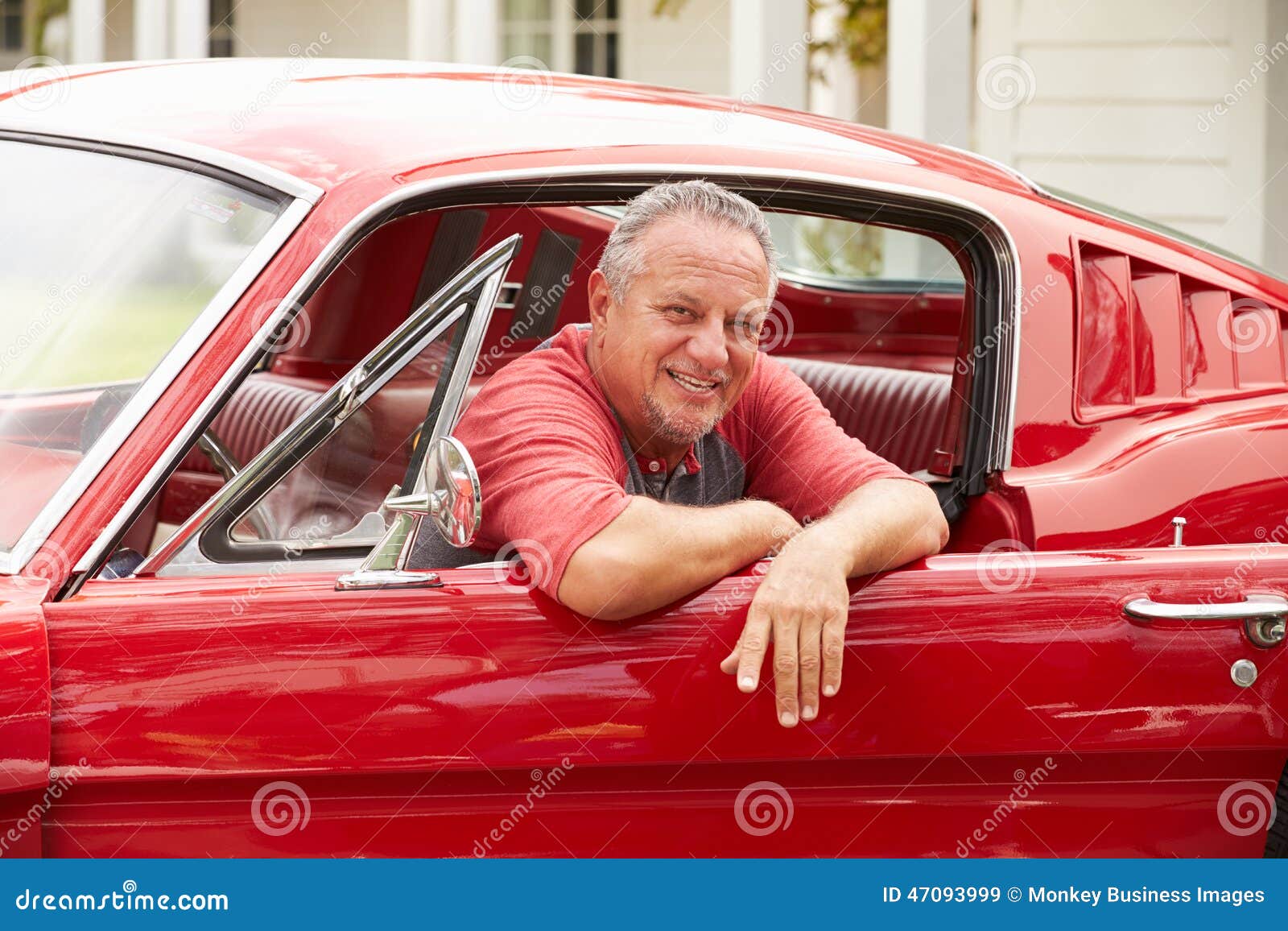 retired senior man sitting in restored classic car