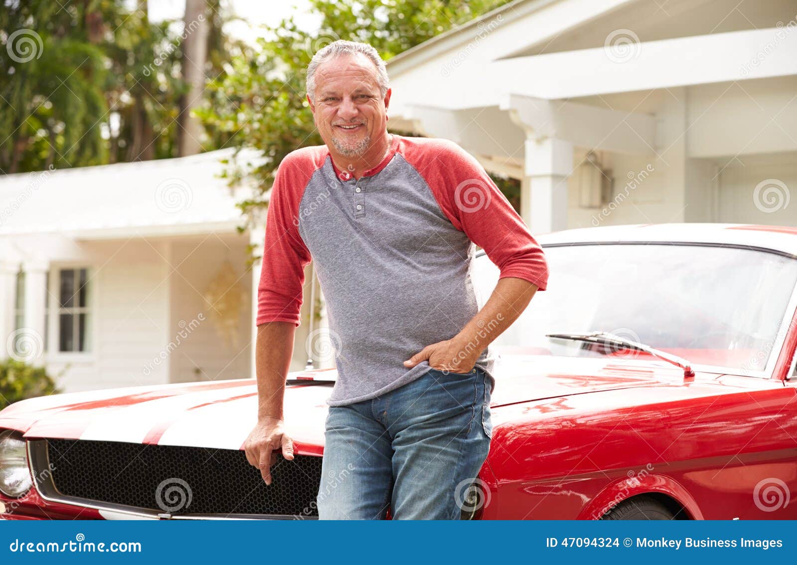 retired senior man standing next to restored classic car