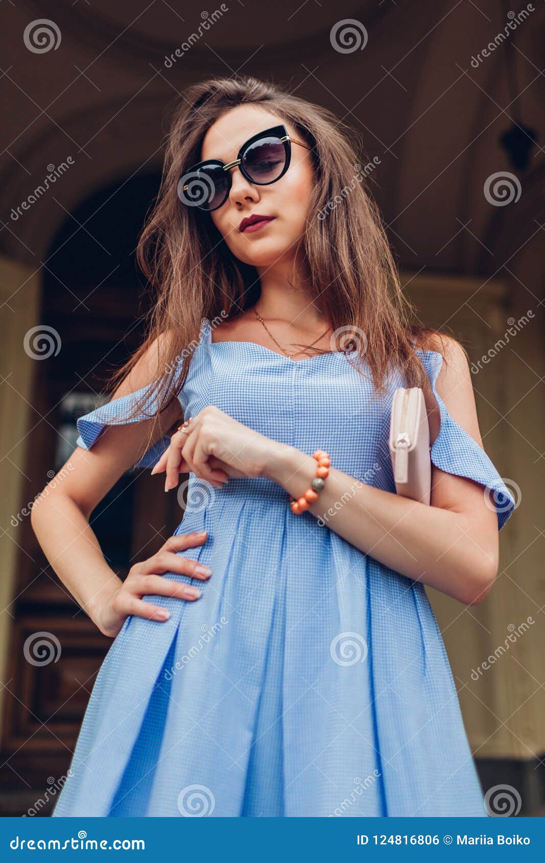 Retrato al aire libre de la mujer hermosa joven que lleva las gafas de sol elegantes y que sostiene el monedero Moda, modelo de l. Retrato al aire libre de la mujer de moda hermosa joven que lleva las gafas de sol elegantes y que sostiene el monedero Moda, equipo modelo del verano de la belleza que lleva