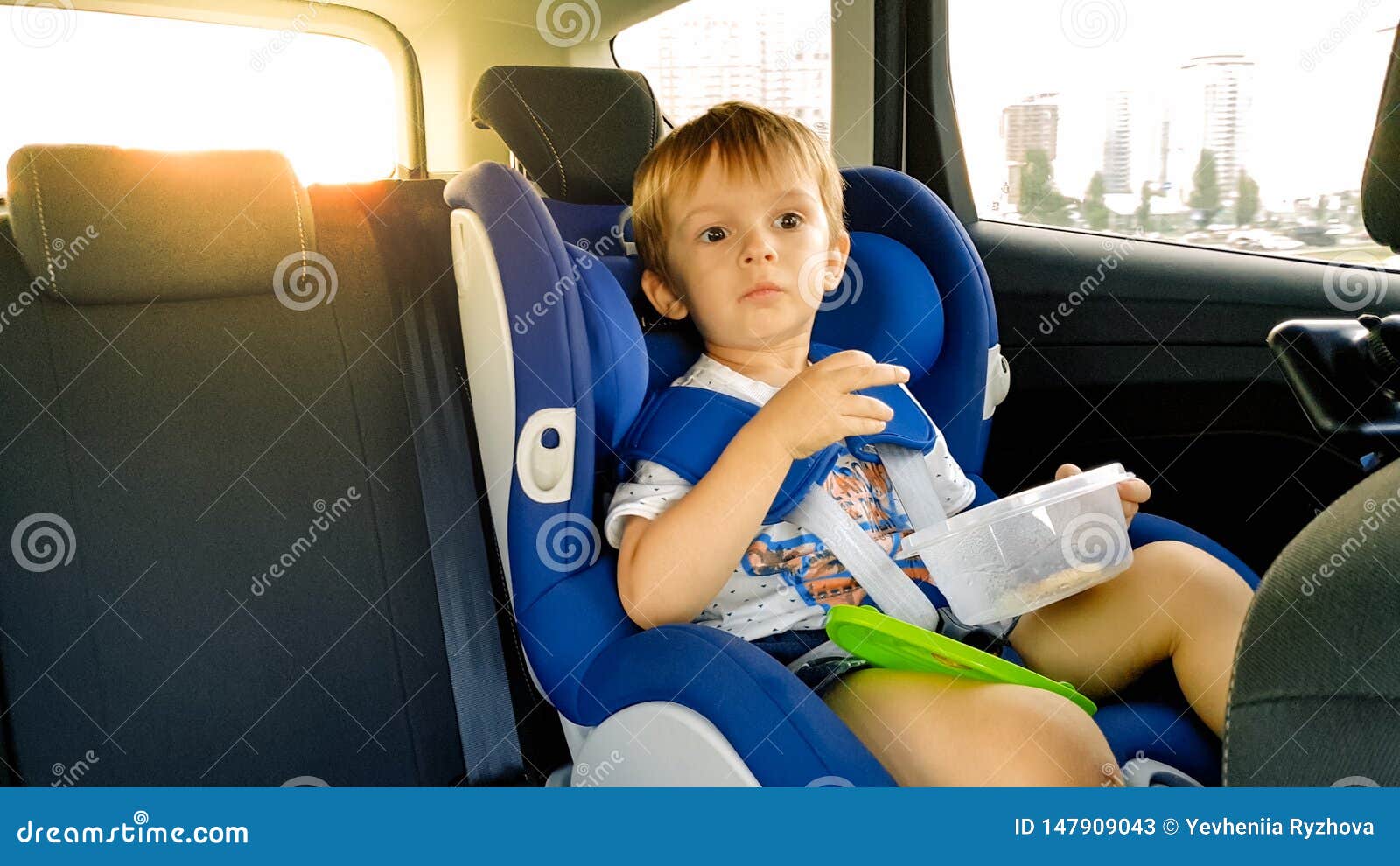 Retrato De 3 Años Del Niño Pequeño Que Se Sienta En Asiento De La Seguridad  Del Niño En Coche Y Que Come Las Galletas Niños Que V Imagen de archivo -  Imagen