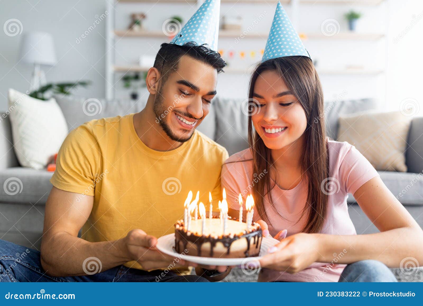 Retrato De Feliz Pareja Multirracial En Sombreros Festivos Sosteniendo Pastel  De Cumpleaños Con Velas Encendidas En Casa Foto de archivo - Imagen de  amor, doméstico: 230383222