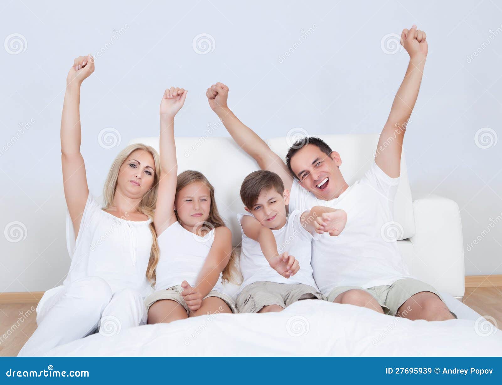 Retrato de la familia feliz que se sienta en cama. Retrato de la familia feliz con dos niños que se sientan en cama en dormitorio