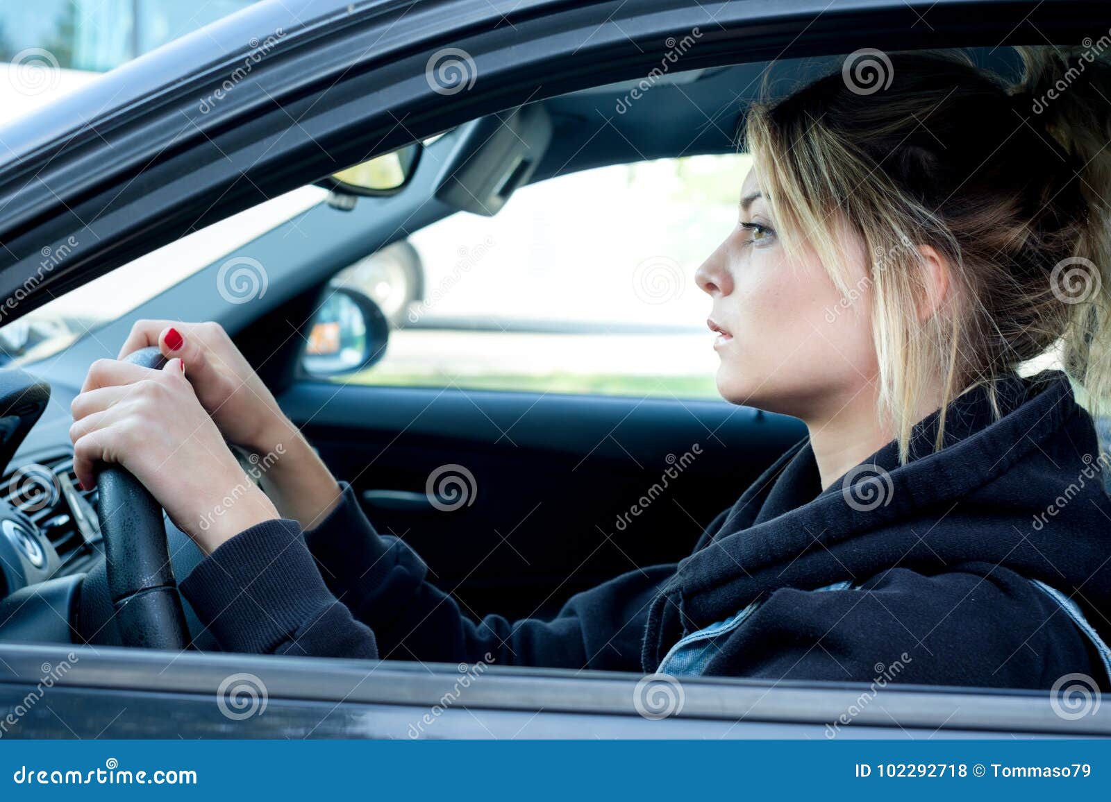 Retrato de la mujer joven que conduce su coche. Mujer que conduce su coche en la calle de la ciudad