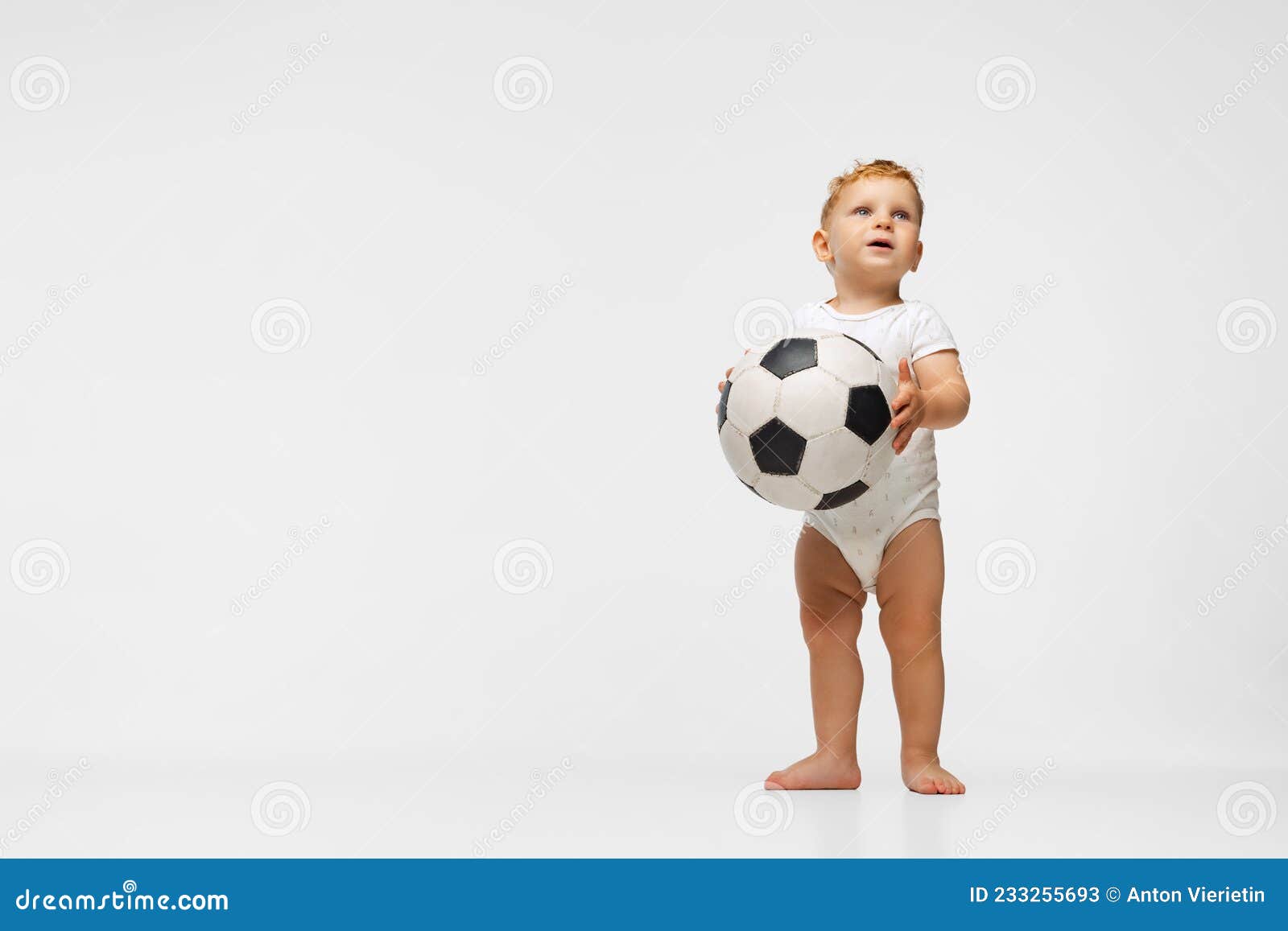 Un niño con una pelota de fútbol sobre un fondo blanco.