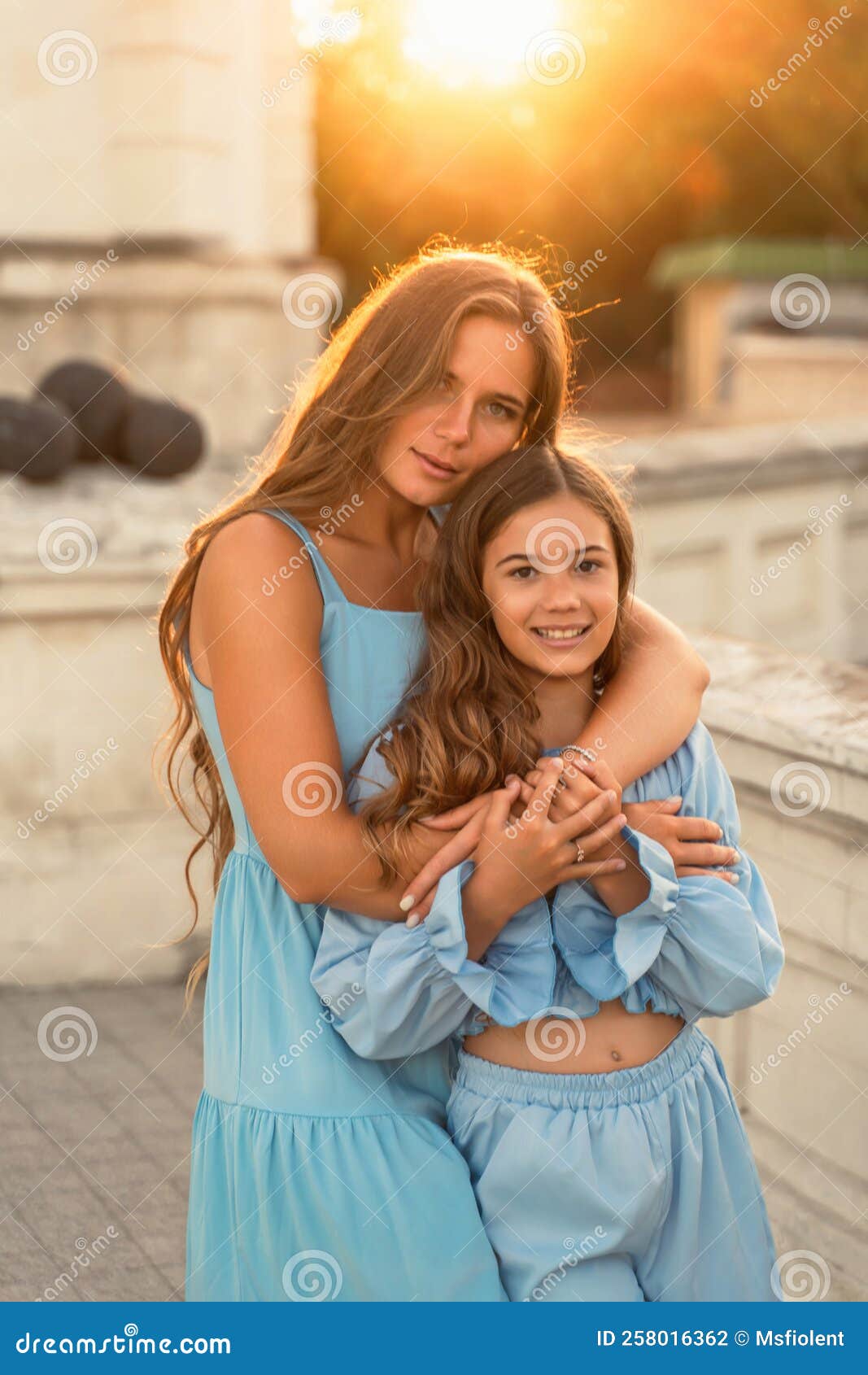 Retrato De Madre E Hija Con Vestidos Azules Con El Pelo Largo Que Fluye El Fondo De La Puesta De La Mujer Foto de - Imagen de azul,
