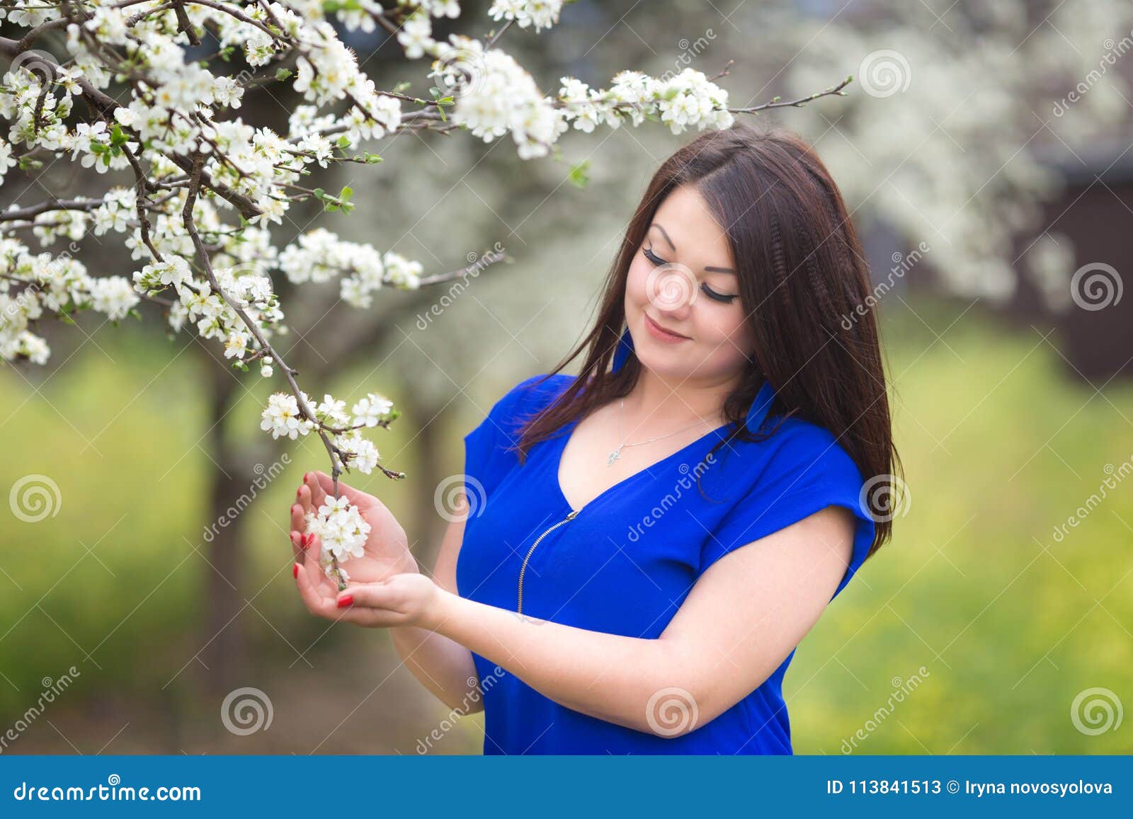 Retrato de uma jovem mulher que guarda uma refeição matinal da árvore de ameixa de florescência em um pomar. Retrato de uma jovem mulher que guarda uma refeição matinal da árvore de ameixa de florescência no pomar Vista ao ramo