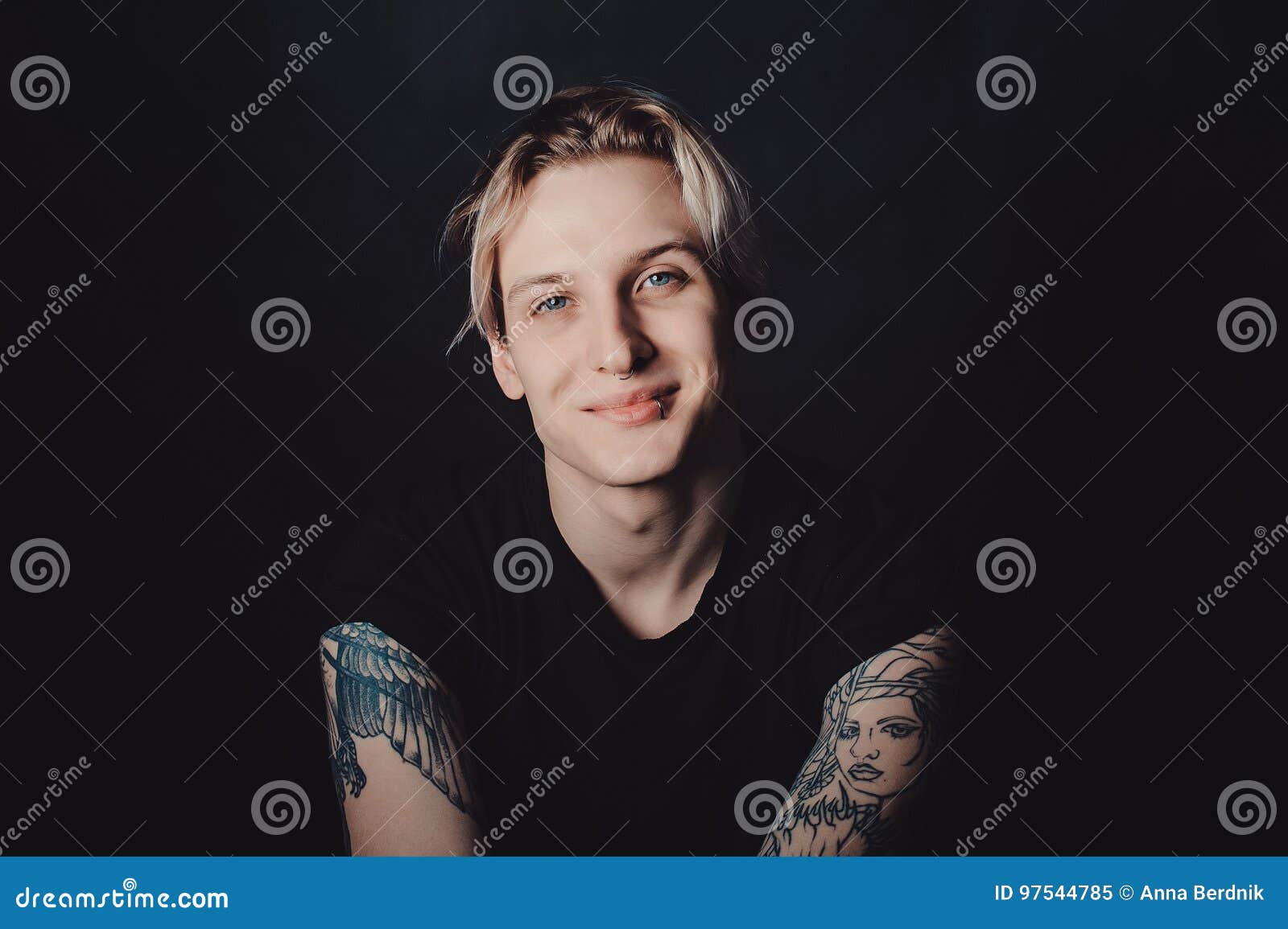 Retrato De Un Individuo Rubio Joven Con Los Tatuajes Y Las Perforaciones En Un Fondo Negro